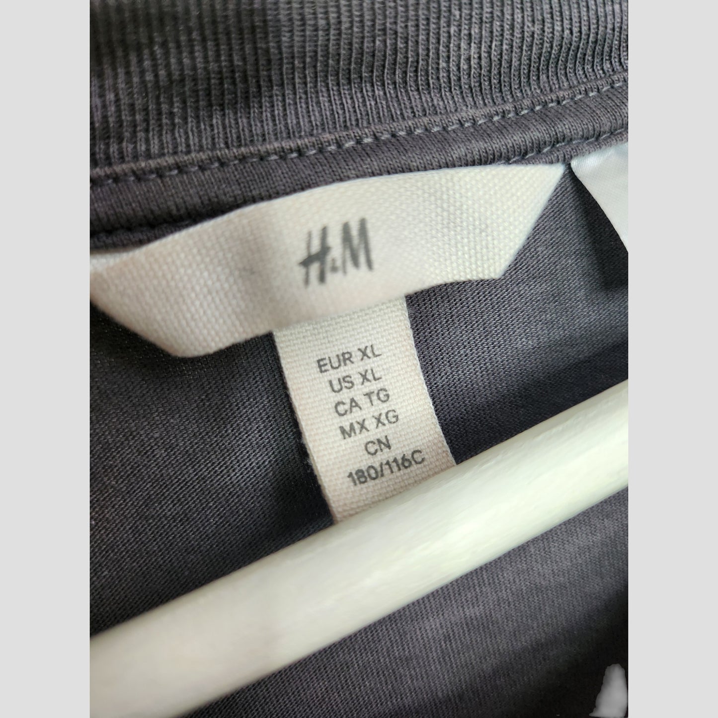 Close-up of an H&M label on an Upcycled Breastfeeding & Pumping Grey Rainbow Pink Floyd Band t-shirt, size EUR XL/US XL/CA TG/MX XG/CN 180/116C—ideal for eco-friendly maternity or preloved nursing wear.