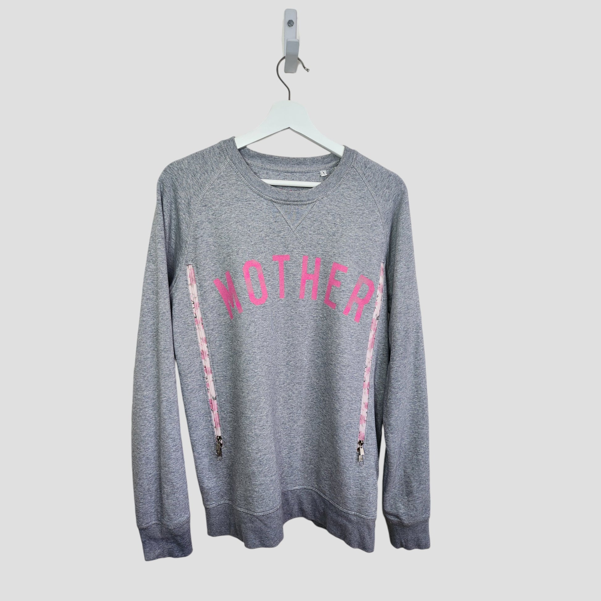 The Selfish Mother Upcycled Breastfeeding & Pumping Grey/Pink MOTHER Sweatshirt (L) features bold pink "MOTHER" lettering on organic cotton, shown on a white hanger against a plain light background.