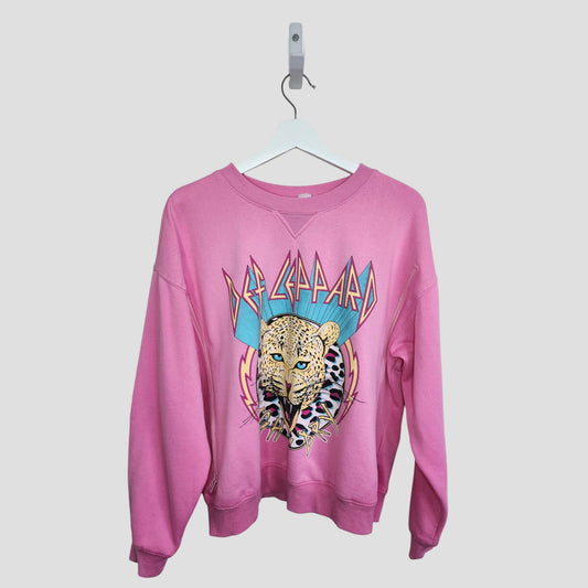 An upcycled pink H&M Def Leppard band sweatshirt (M, 100131), designed for breastfeeding and pumping, features a bold leopard graphic and text on the front. Shown hanging on a white hanger against a light background.