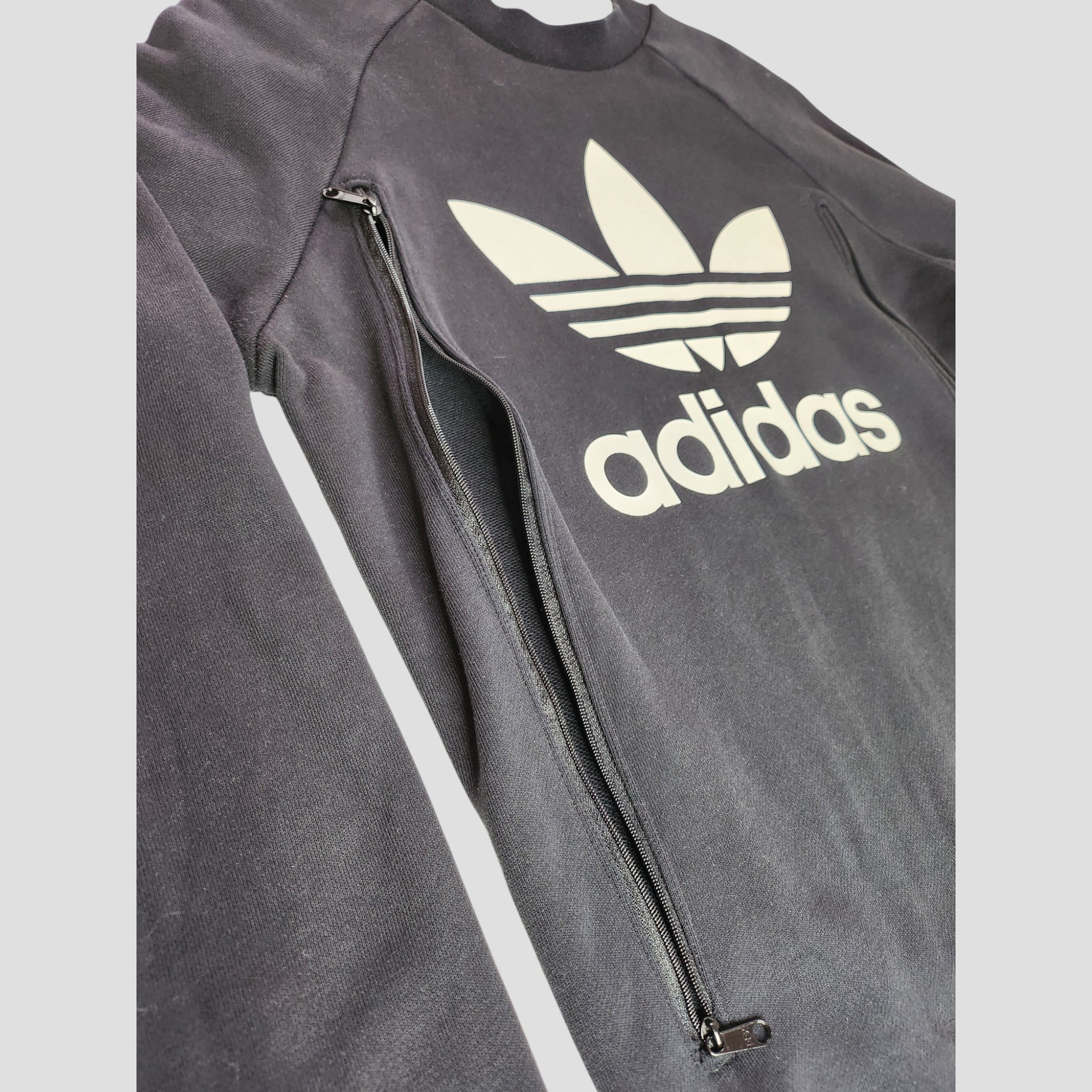 The Upcycled Breastfeeding & Pumping Black/White Adidas Sweatshirt UK14 (100271) features the white Trefoil logo and adidas text on the front, plus eco-friendly black zippers along both sides for nursing comfort and style.