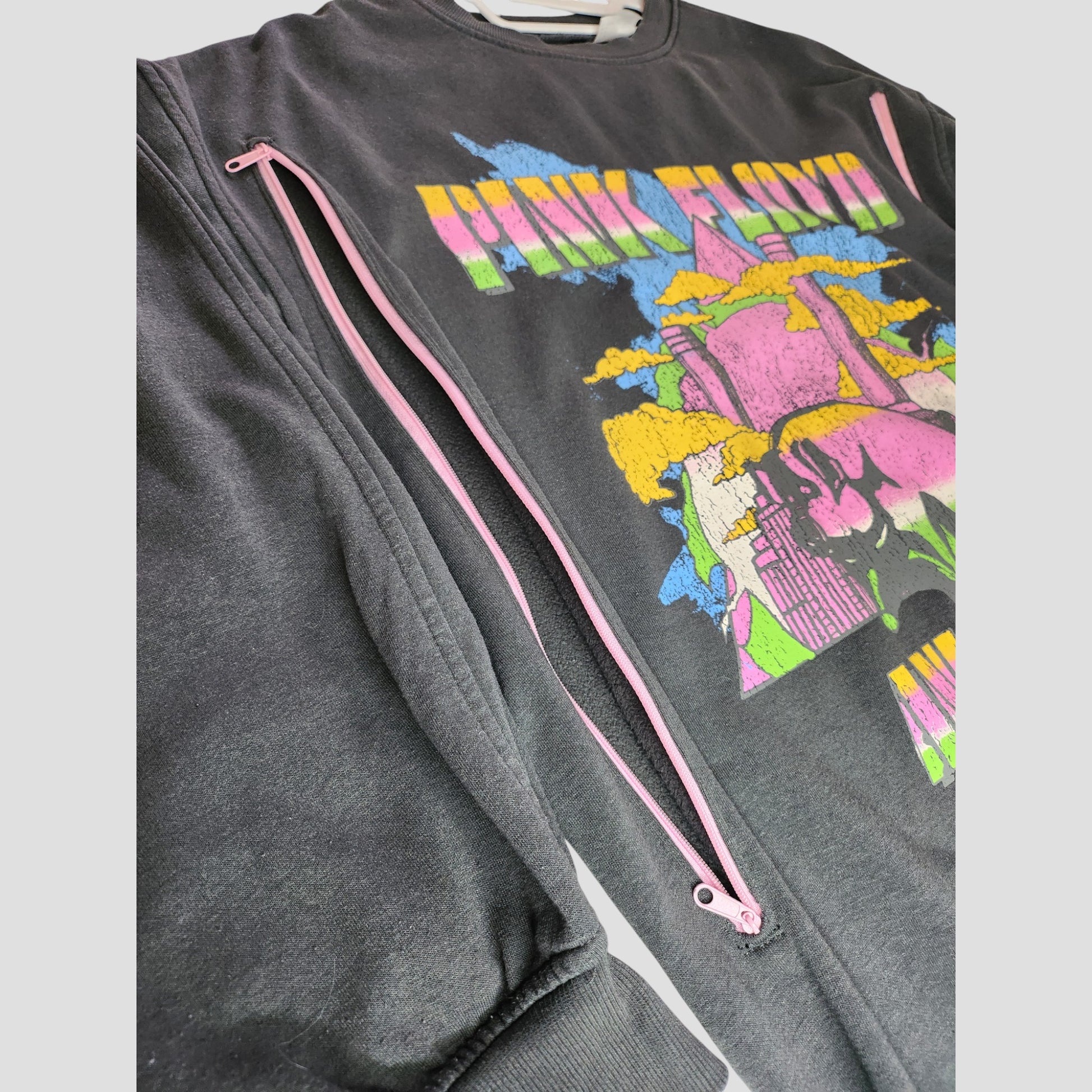 Primark Upcycled Breastfeeding & Pumping Pink Floyd Long Oversized Band Sweatshirt (M, UK12/14) features pink zipper accents and a colorful abstract city-and-clouds graphic with partially hidden yellow and pink text, crafted from upcycled materials.