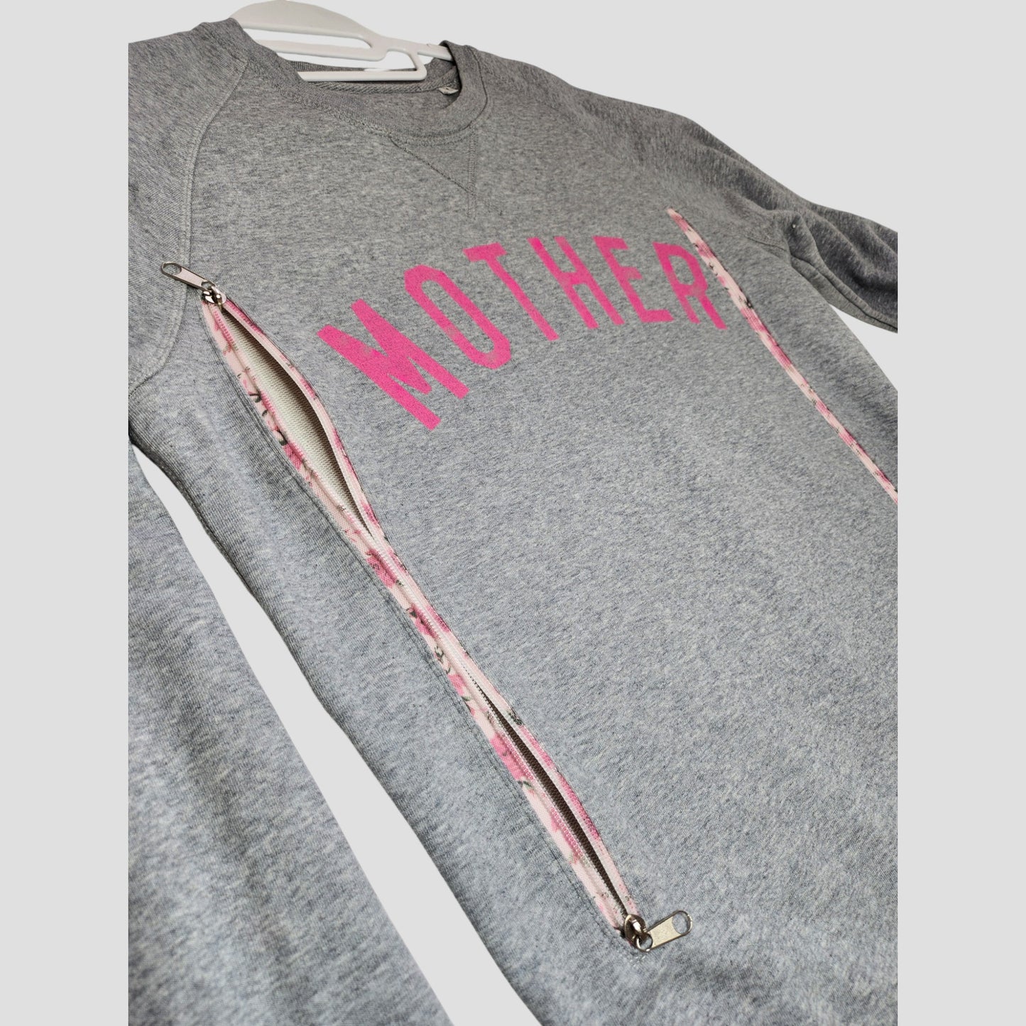 The Selfish Mother Upcycled Breastfeeding (Nursing) & Pumping Grey/Pink MOTHER Sweatshirt L features pink "MOTHER" text, angled side zippers for easy nursing, and a pink and white inner lining—perfect for breastfeeding or pumping.