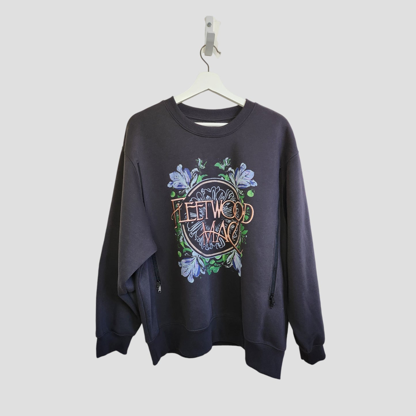 The Primark Upcycled Breastfeeding & Pumping Embroidered Fleetwood Mac Band Oversized Sweatshirt (L) is shown on a white hanger against a light gray background, featuring colorful graphics and floral details.