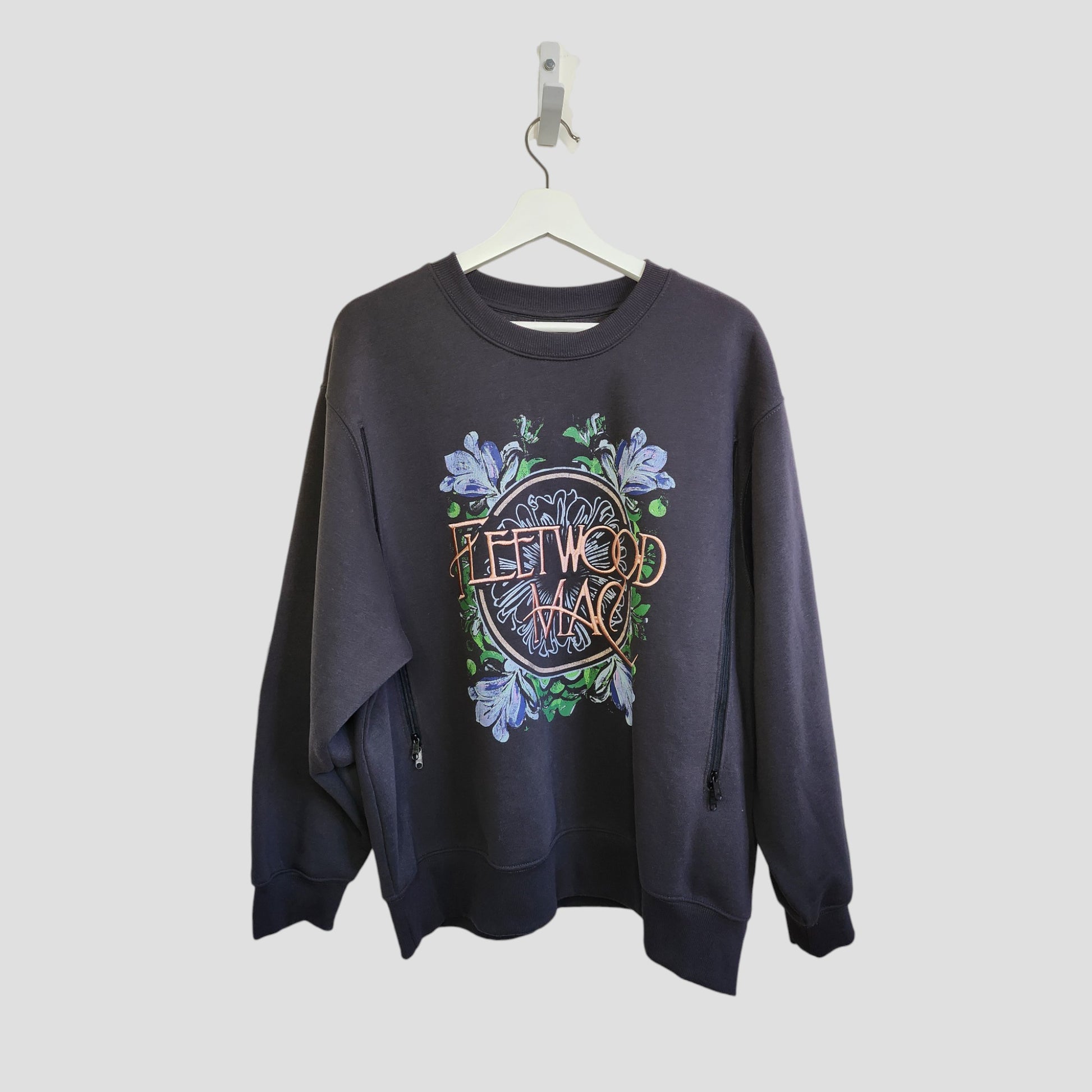 The Primark Upcycled Breastfeeding & Pumping Embroidered Fleetwood Mac Band Oversized Sweatshirt (L) is shown on a white hanger against a light gray background, featuring colorful graphics and floral details.