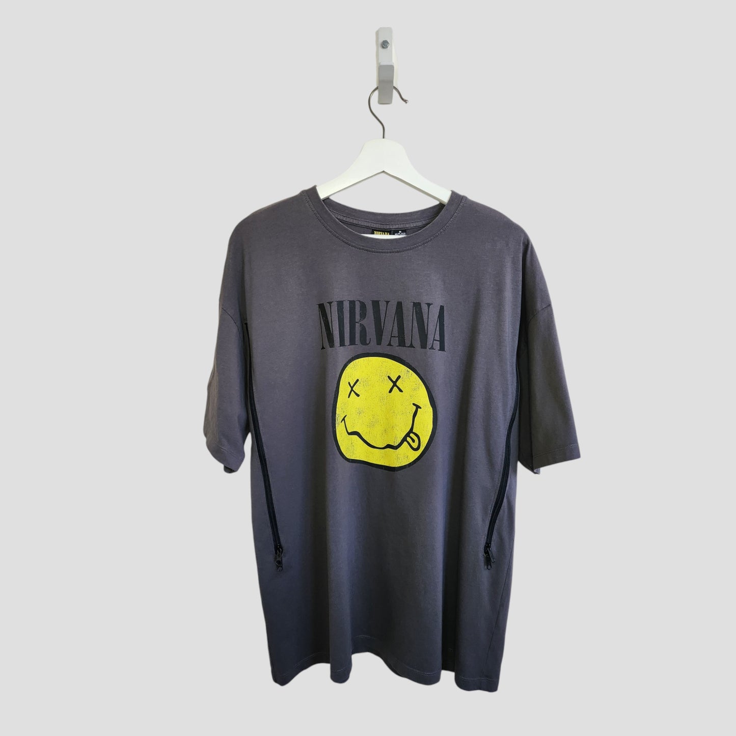 A grey/yellow upcycled Primark Nirvana t-shirt (size M, UK12/14) for breastfeeding and pumping, featuring the band name above a yellow smiley face logo with crossed-out eyes and a squiggly mouth.