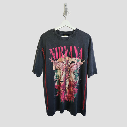 A dark grey floral Nirvana band oversized t-shirt by Primark hangs on a white hanger. This upcycled nursing and pumping tee (UK10/12) features a colorful angel and flower graphic with “NIRVANA” in bold pink letters across the chest.