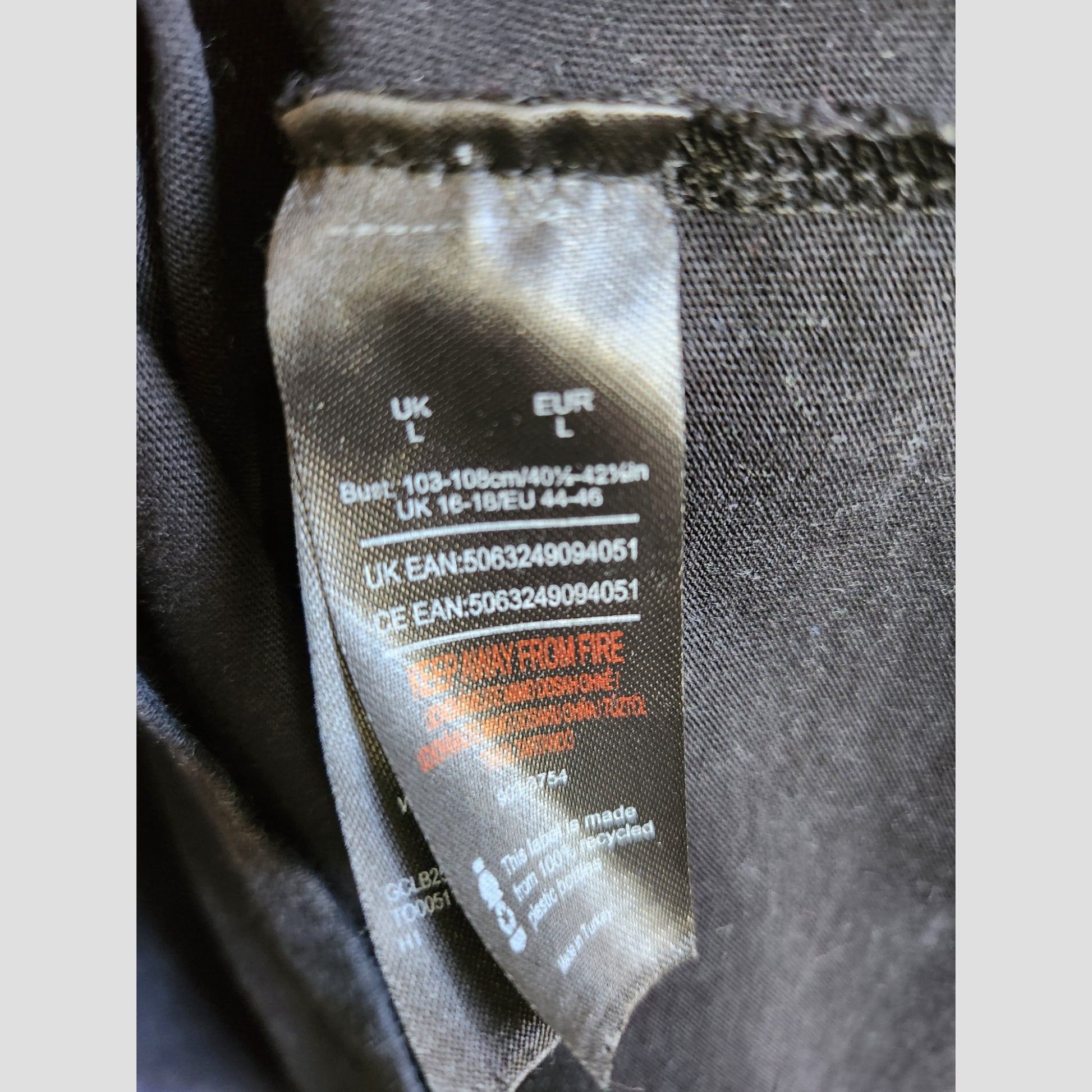 A close-up of a black Def Leppard label (UK L, EUR L) with bust details and red KEEP AWAY FROM FIRE warning—ideal for eco-friendly preloved Upcycled Breastfeeding & Pumping Def Leppard Snow Band t-shirt L (100344) collections.