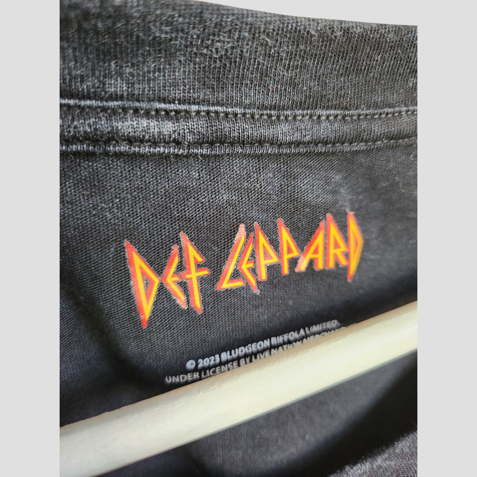 Close-up of an upcycled Def Leppard Snow Band T-shirt (size L), perfect for breastfeeding and pumping—features yellow and red band logo on black, offering sustainable style for fans. Brand: Def Leppard.