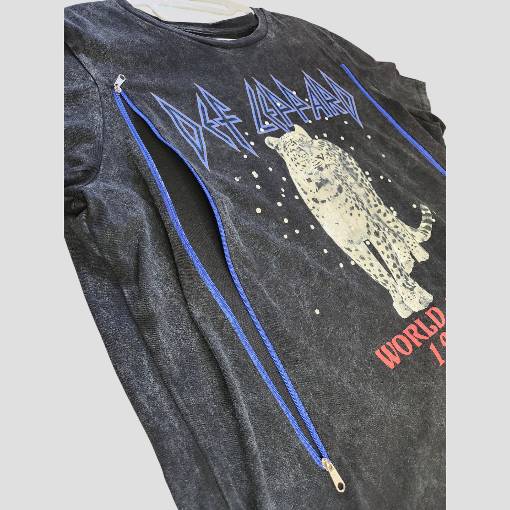 This upcycled Def Leppard Snow Band T-shirt (L, 100344) features blue text, a white leopard graphic, red World Tour 1987 print, and diagonal blue zippers—an eco-friendly nursing/pumping top made from preloved clothing.