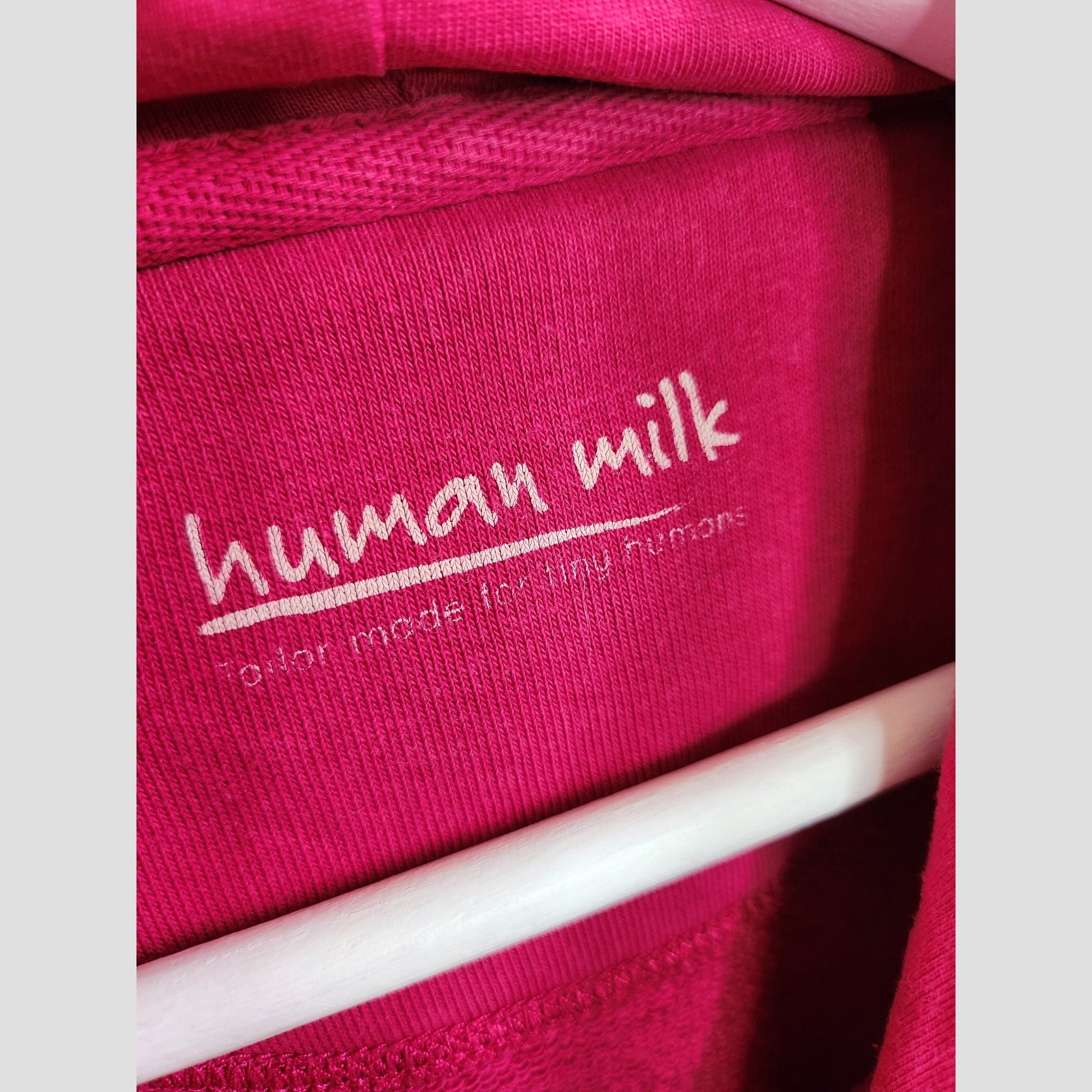 Close-up of a pink fabric label with “Human Milk” in white and beneath, smaller text: “not made for tiny humans”—featured on the Upcycled Breastfeeding & Pumping Human Milk Composition Hoodie L by Human Milk.