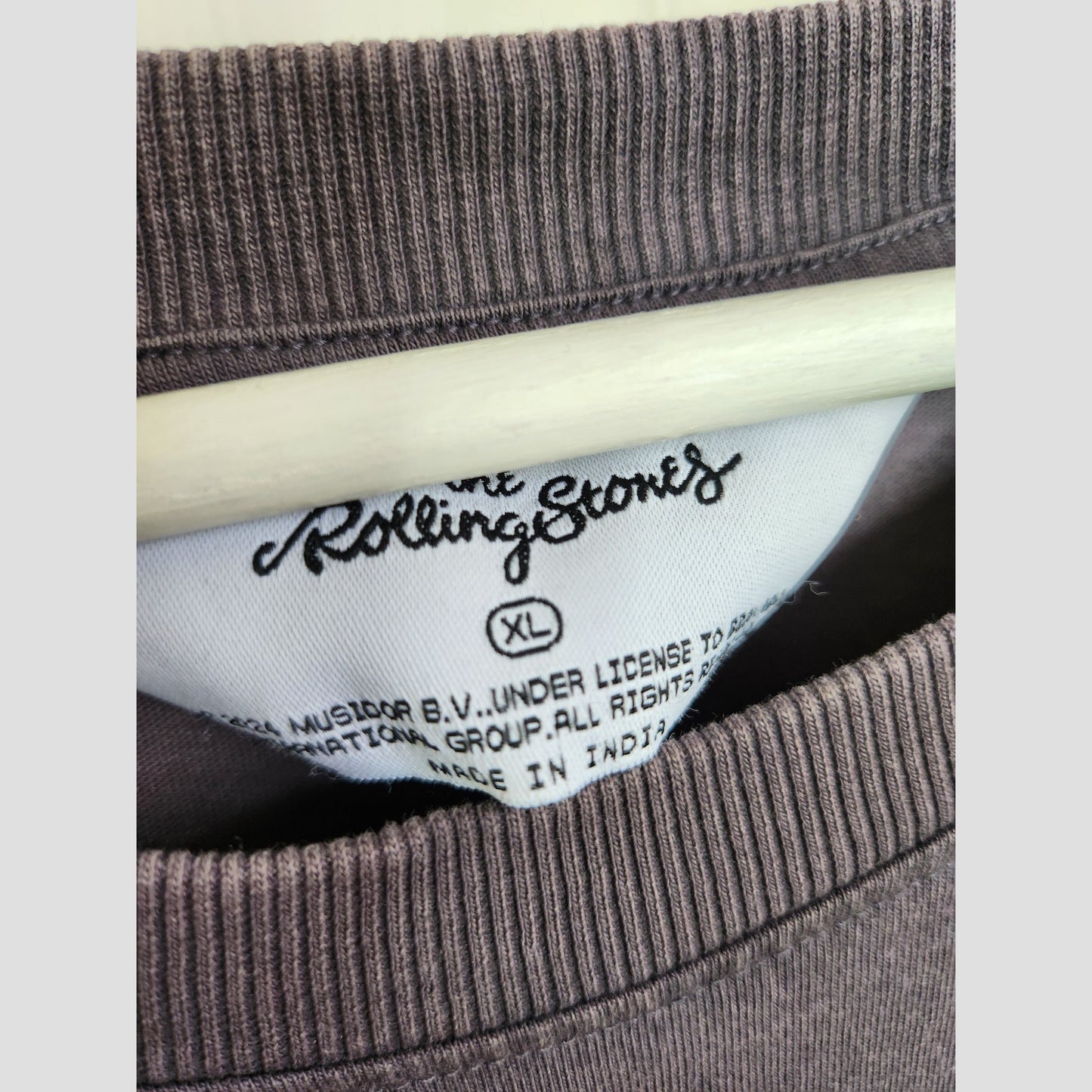 Close-up of a Primark clothing tag inside a brown Upcycled Breastfeeding & Pumping The Rolling Stones US Tour Band t-shirt, size XL (UK18/20)—ideal for fans seeking sustainable maternity or nursing wear.