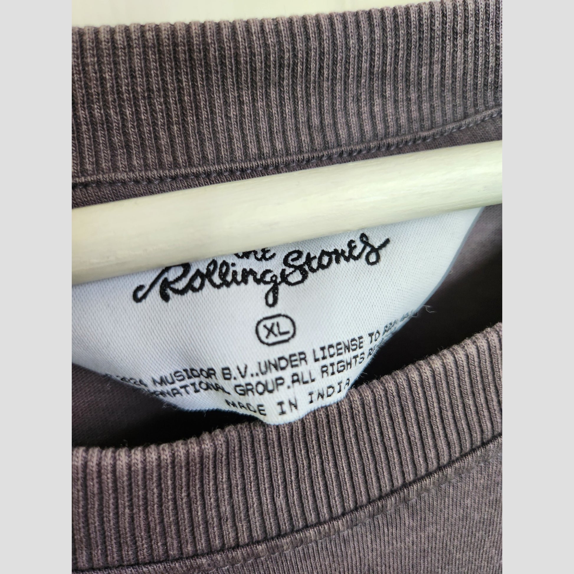 Close-up of a Primark clothing tag inside a brown Upcycled Breastfeeding & Pumping The Rolling Stones US Tour Band t-shirt, size XL (UK18/20)—ideal for fans seeking sustainable maternity or nursing wear.