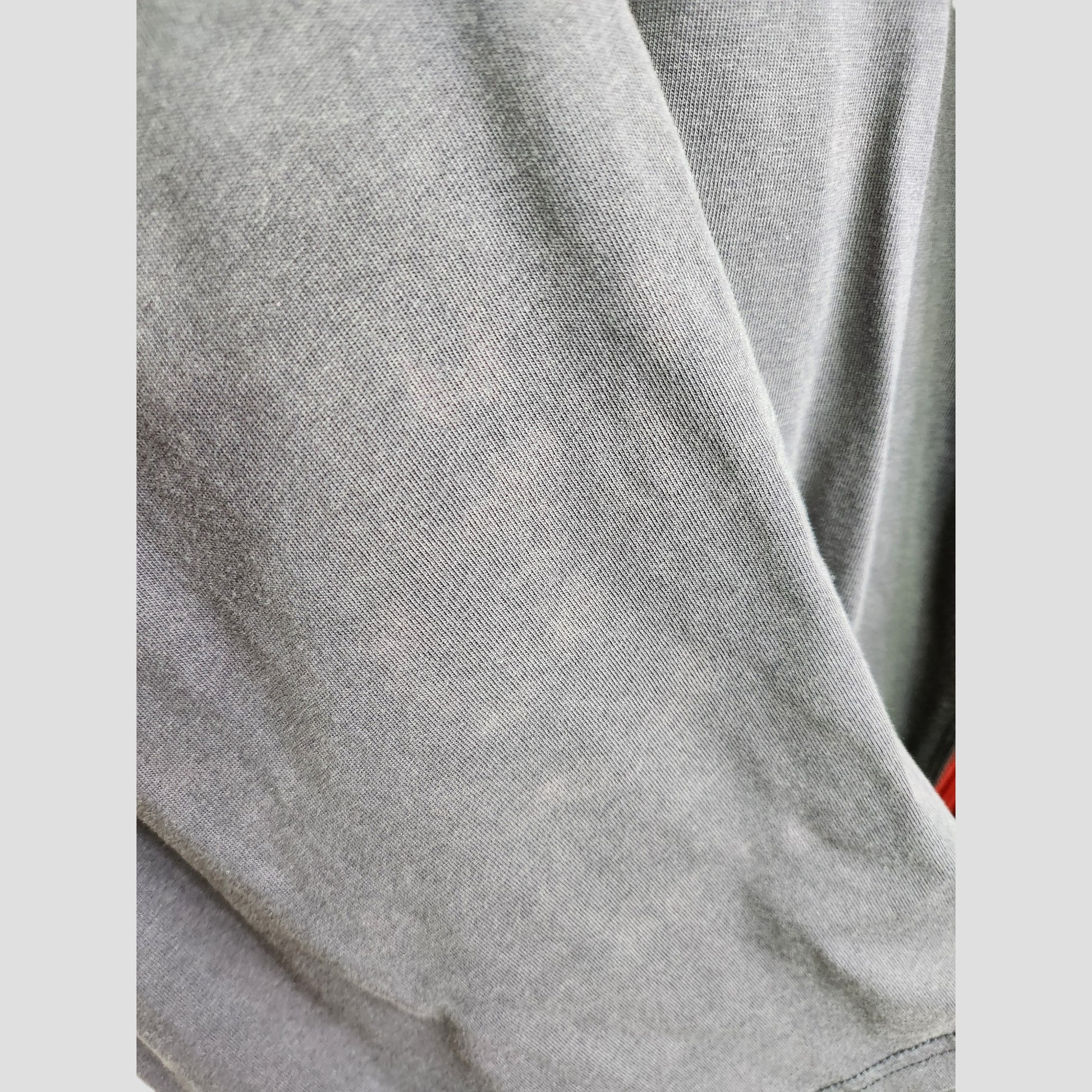 A close-up of soft gray fabric from Primark’s Upcycled Breastfeeding & Pumping The Rolling Stones US Tour Band t-shirt XL (UK18/20), showing its fine texture, gentle folds, and subtle heathered look.