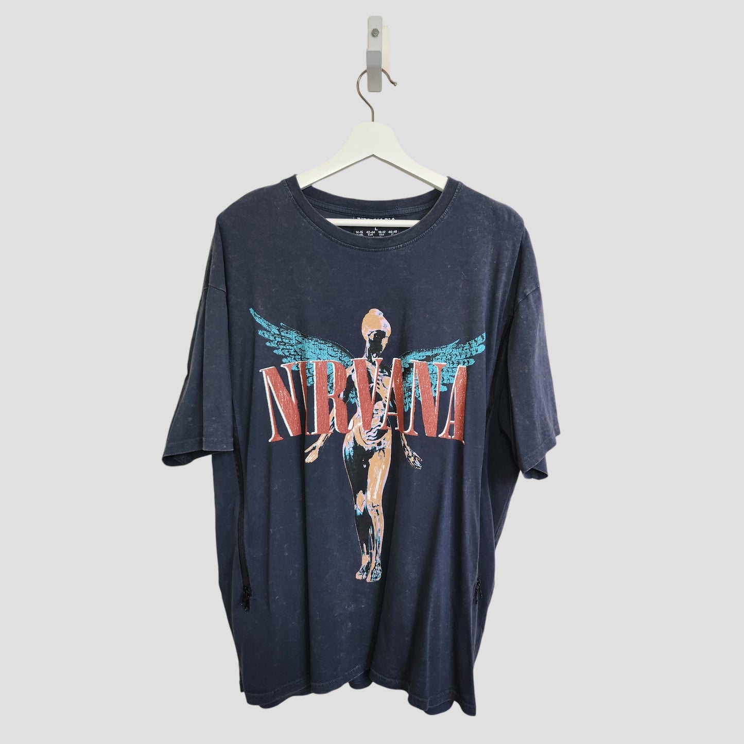 An upcycled Primark Nirvana band T-shirt (L, UK14/16) in grey/turquoise with a winged anatomical figure and bold red band name—eco-friendly nursing & pumping style with iconic appeal.