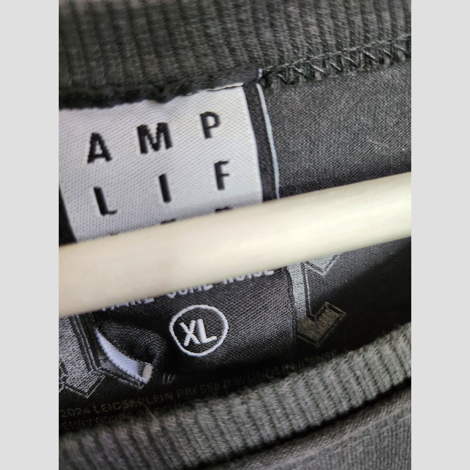 Close-up of a black clothing tag on a hanger, showing "Amplified" and XL—highlighting this upcycled nursing & pumping grey AC/DC band t-shirt (XL, 100317), perfect for eco-conscious maternity style.