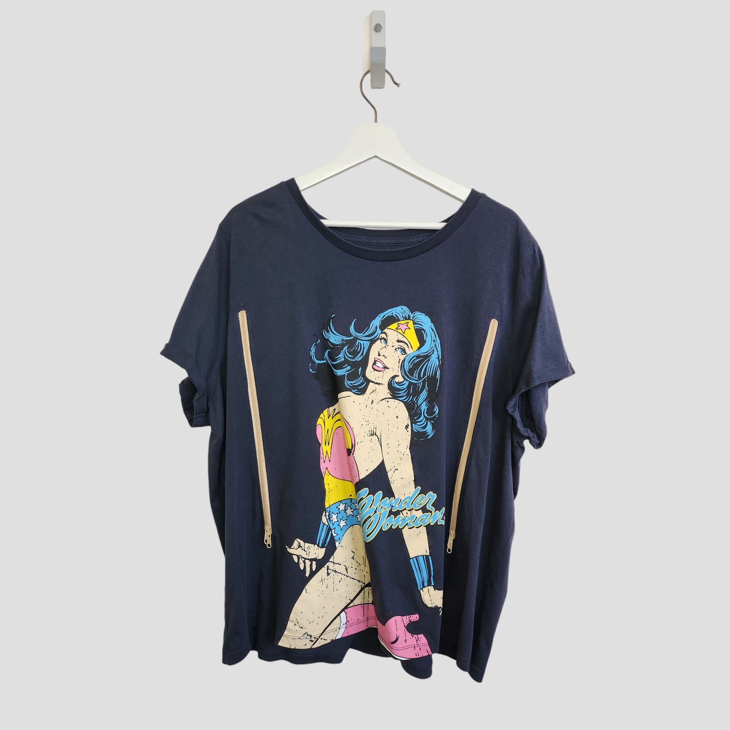 The Tu Upcycled Breastfeeding & Pumping Navy Wonder Women T-shirt UK24 features comic-style graphics and two vertical beige zippers for easy nursing access—perfect for those seeking stylish, upcycled breastfeeding wear.