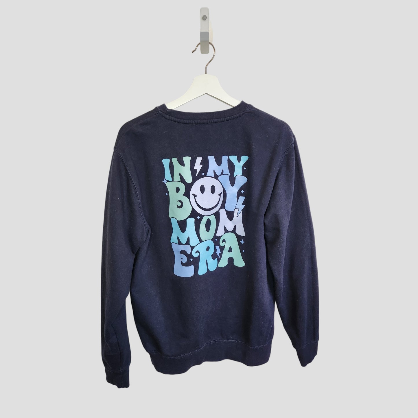 The Upcycled Breastfeeding & Pumping Boy Mom Era Sweatshirt by My Rocking Kids features "IN MY BOY MOM ERA" in bold blue and teal on navy, a smiley face graphic on the back, and is eco-friendly maternity wear, size M (100142).