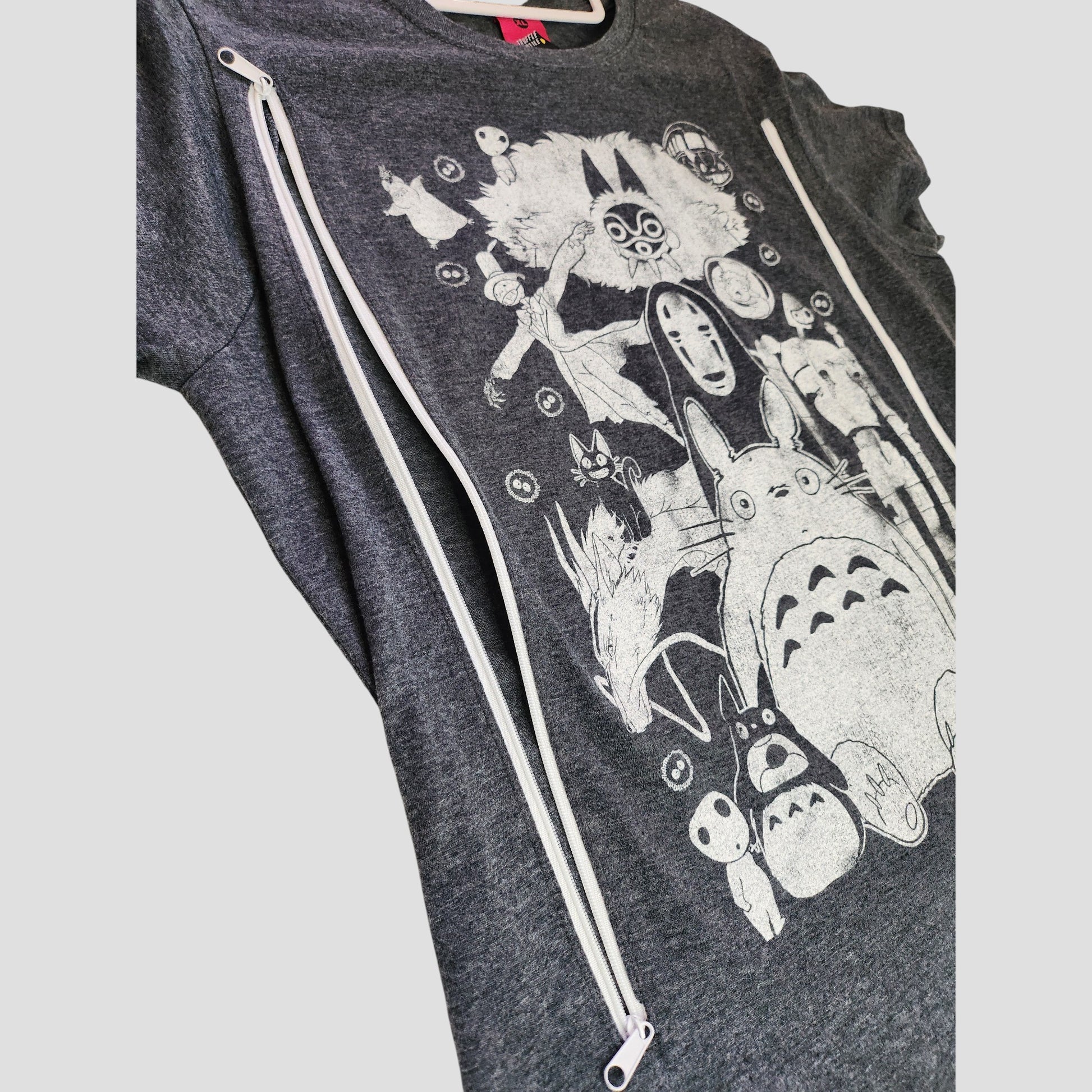 The Truffle Shuffle Upcycled Breastfeeding & Pumping Washed Out Totoro t-shirt XL features white Studio Ghibli illustrations and two diagonal zippers for easy access—ideal, affordable pumping wear for moms. Displayed on a plain light background.