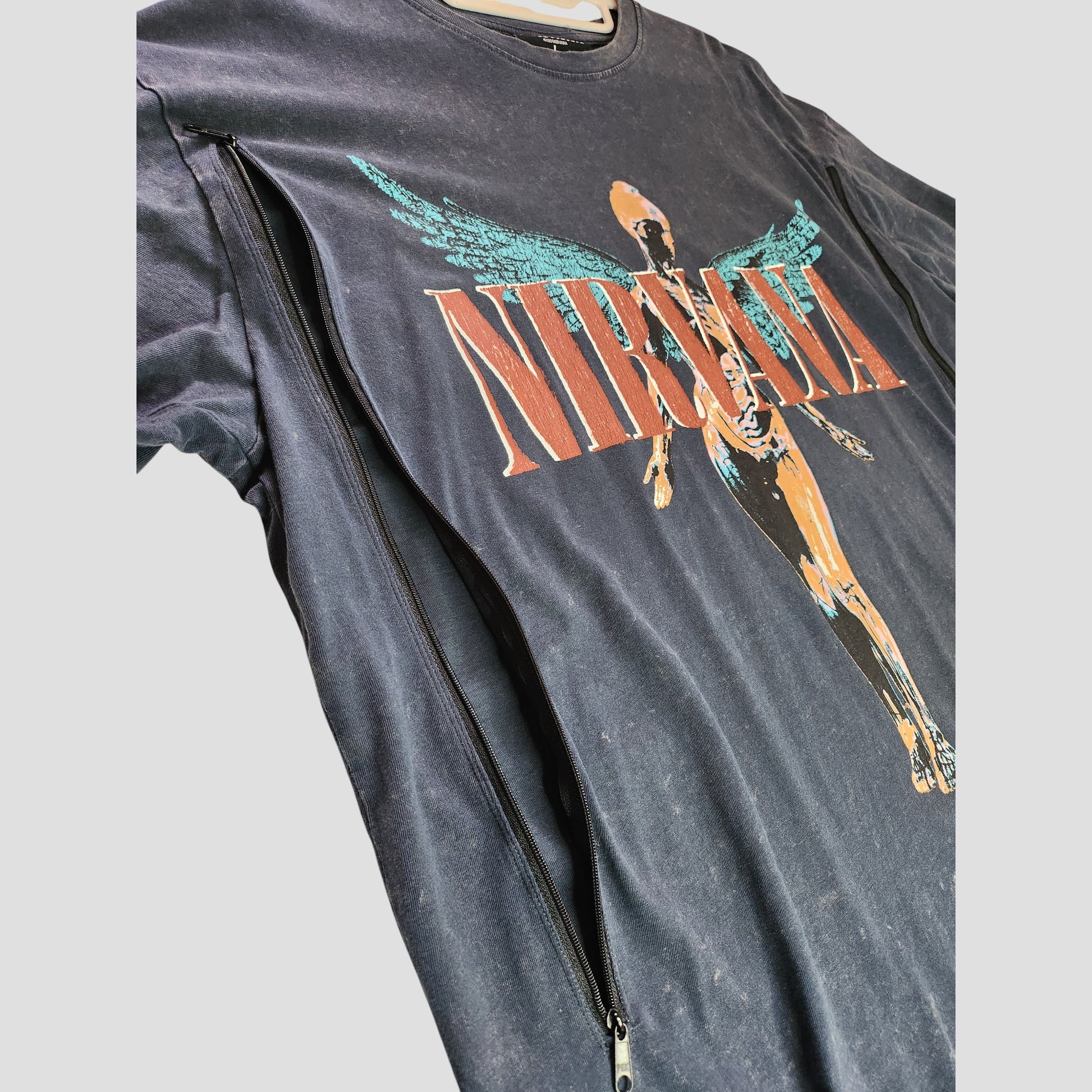 Close-up of Primark's upcycled Nirvana Band T-shirt (L, UK14/16) in grey/turquoise, featuring an anatomical angel graphic and a discreet side zipper for breastfeeding or pumping, made from repurposed preloved clothing.