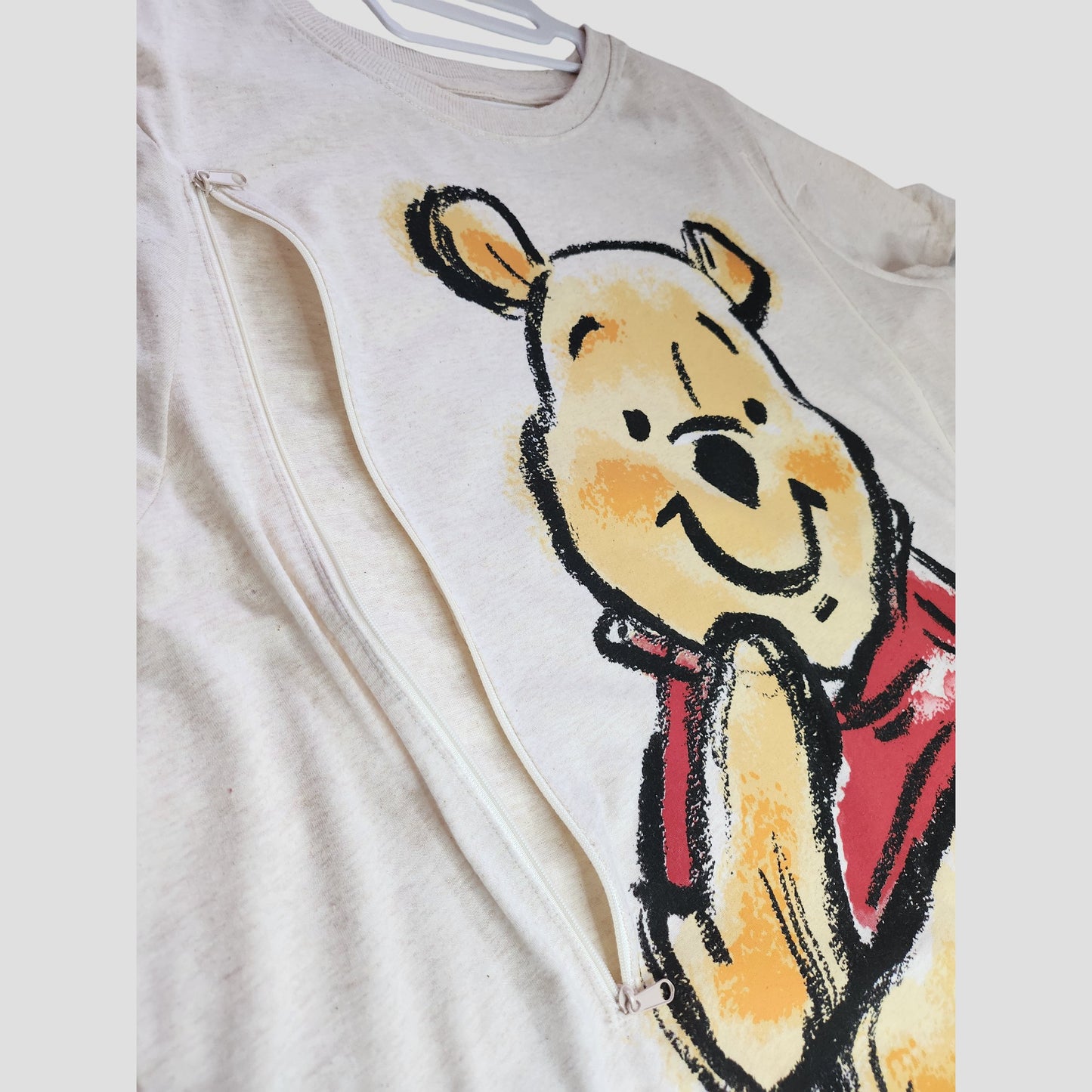 The Primark Upcycled Cream Winnie the Pooh Nursing & Pumping t-shirt (2XL, UK22/24) features a smiling Pooh design and side zipper for breastfeeding—ideal eco-friendly maternity wear for Disney fans.