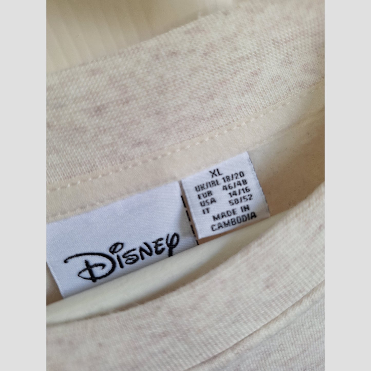 Close-up of a white Primark label inside an upcycled Winnie the Pooh nursing & pumping sweatshirt, size XL (UK18/20), made in Cambodia—a perfect eco-friendly find for maternity wear fans.