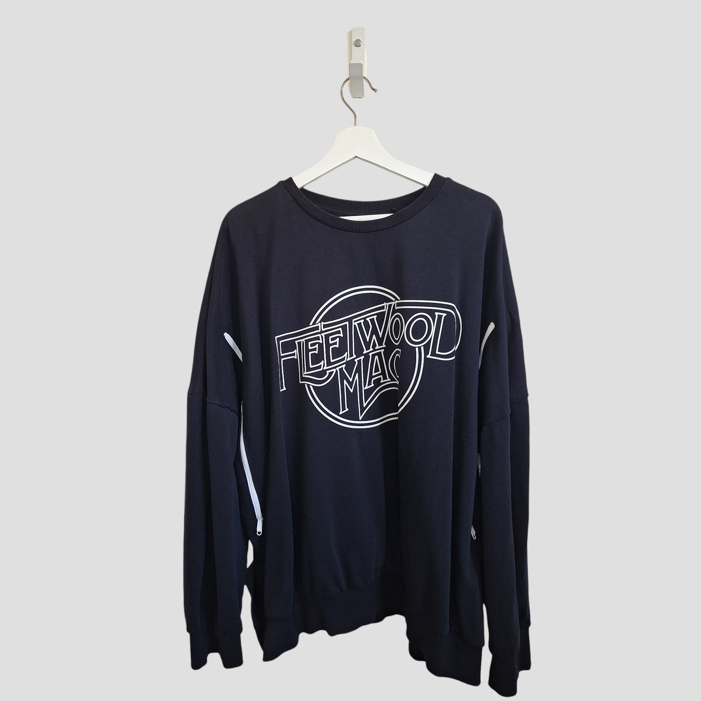 The George Upcycled Breastfeeding & Pumping Black Fleetwood Mac Band Sweatshirt 2XL (100007) with white lettering hangs on a white hanger against a light gray background.