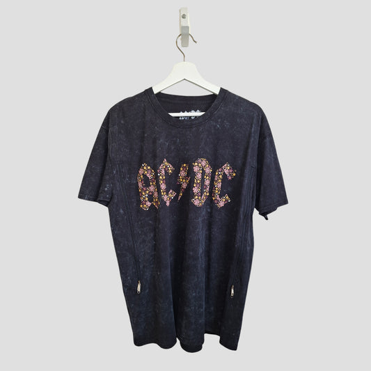 The AC/DC Upcycled Breastfeeding & Pumping Black Floral Band t-shirt (L, 100387) hangs on a white hanger against a plain light gray background.