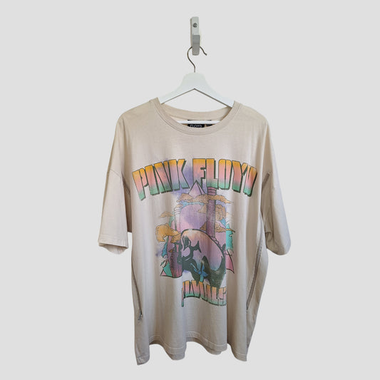 The Primark Upcycled Breastfeeding & Pumping Cream Pink Floyd Band T-shirt (XL, UK18/20) is made from preloved clothing and features a colorful graphic with an abstract design. It hangs on a white hanger against a plain background.