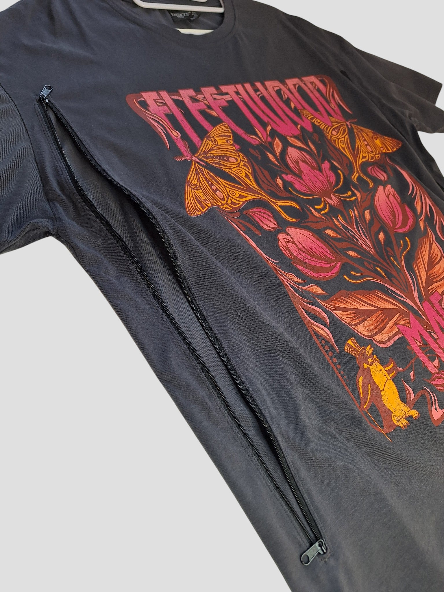 The Primark Upcycled Breastfeeding & Pumping Floral Fleetwood Mac Band t-shirt (M, UK12/14) features a bold graphic and diagonal zipper for nursing—stylish and practical for moms.