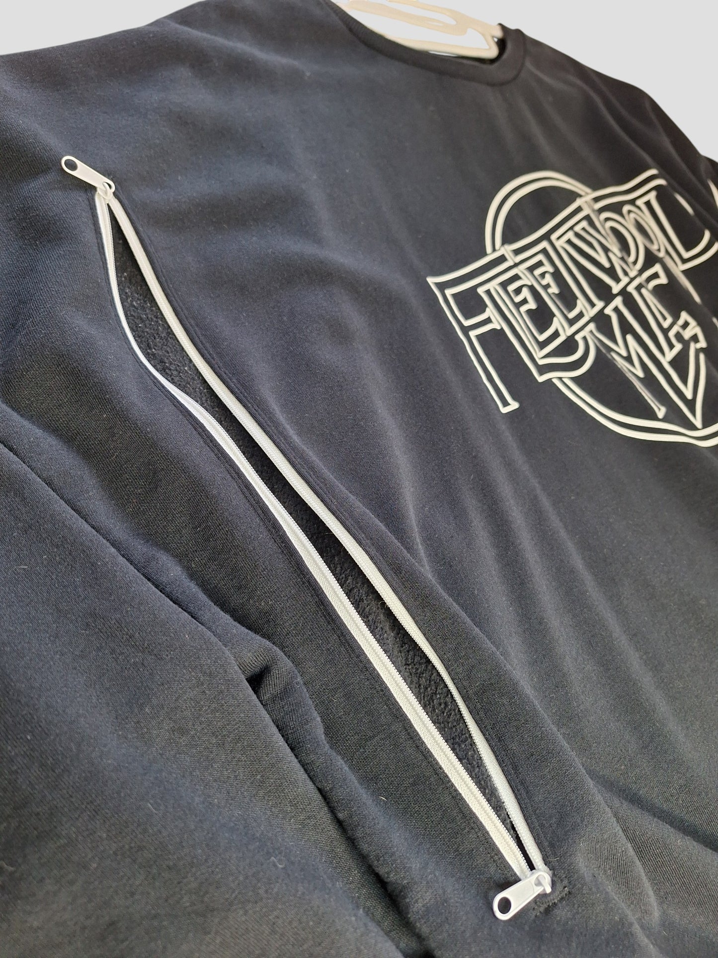 The George Upcycled Breastfeeding & Pumping Black Fleetwood Mac Band Sweatshirt 2XL (100007) features a bold FEED NOT ME chest print and a diagonal white sleeve zipper, all crafted from repurposed nursing clothing.