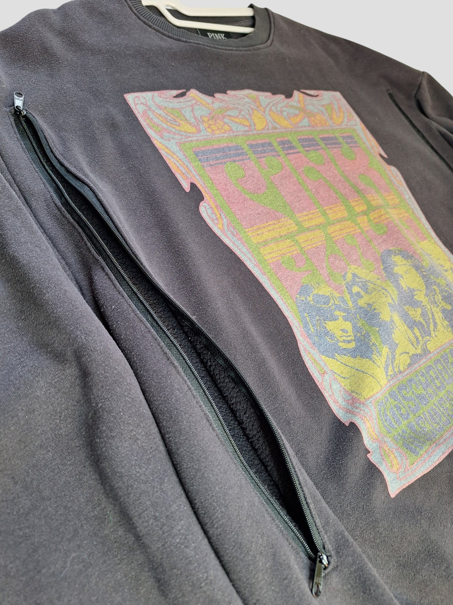A grey Pink Floyd band sweatshirt by Primark, size M (UK12/14), made from upcycled breastfeeding clothing. Features a colorful chest graphic and diagonal zip pocket; inner collar label reads PAIX.