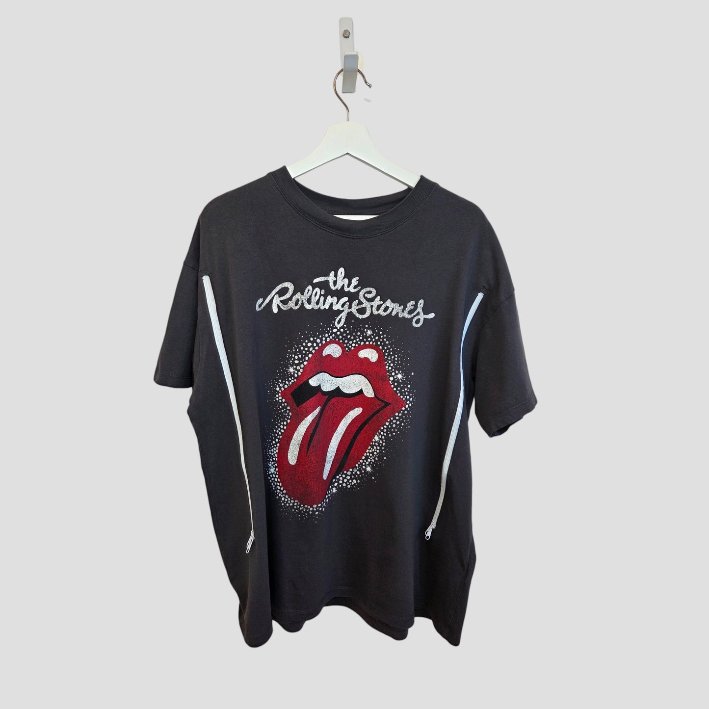A grey and red Upcycled Breastfeeding & Pumping Rolling Stones Band t-shirt (L) by H&M features white stars and the iconic band logo with a red tongue, shown on a hanger against a plain gray background.