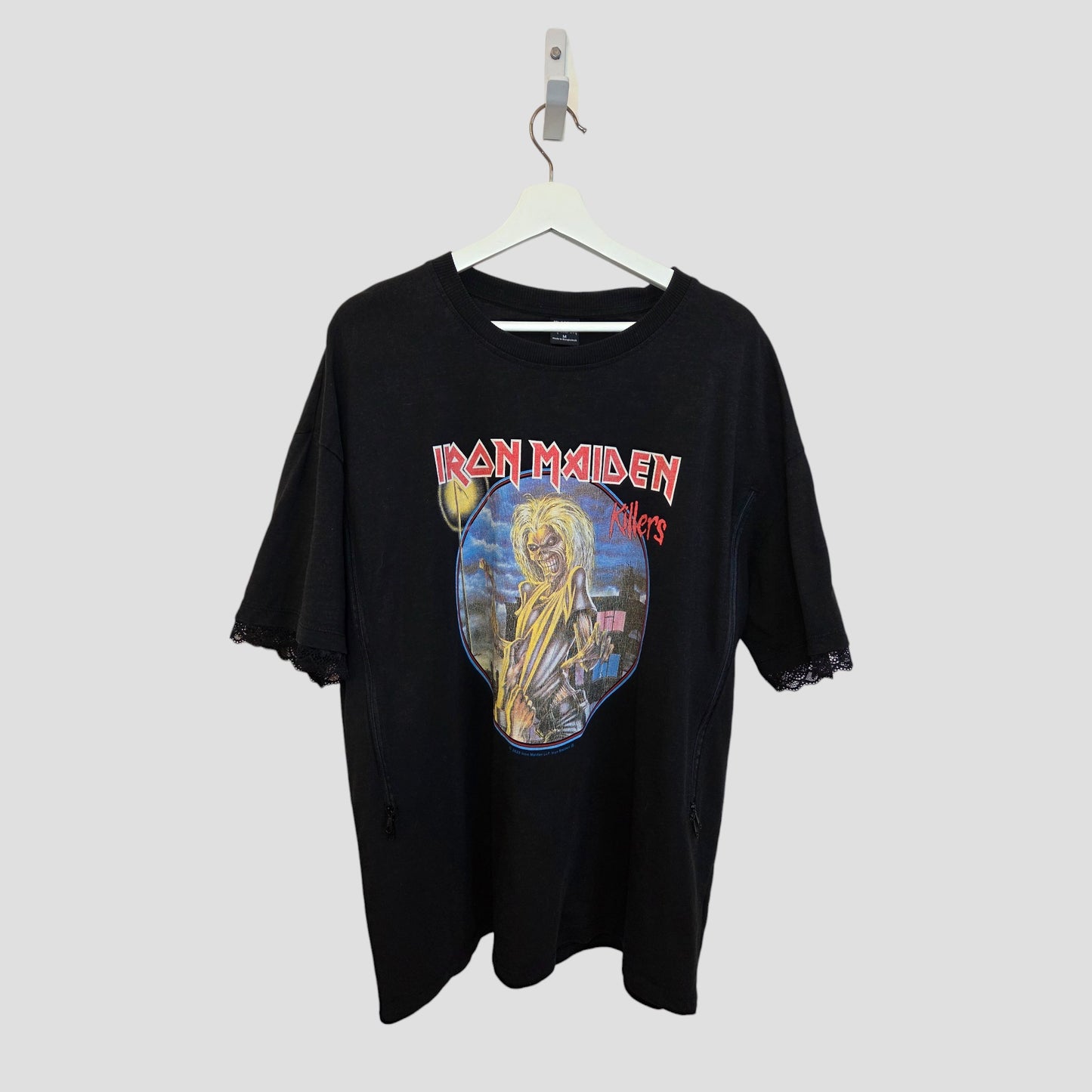 The Primark Upcycled Breastfeeding & Pumping Black Iron Maiden Oversized Band T-shirt (M, 100417) features the Killers album cover and offers a metal-inspired nursing option for moms. Shown on a white hanger against a light gray background.