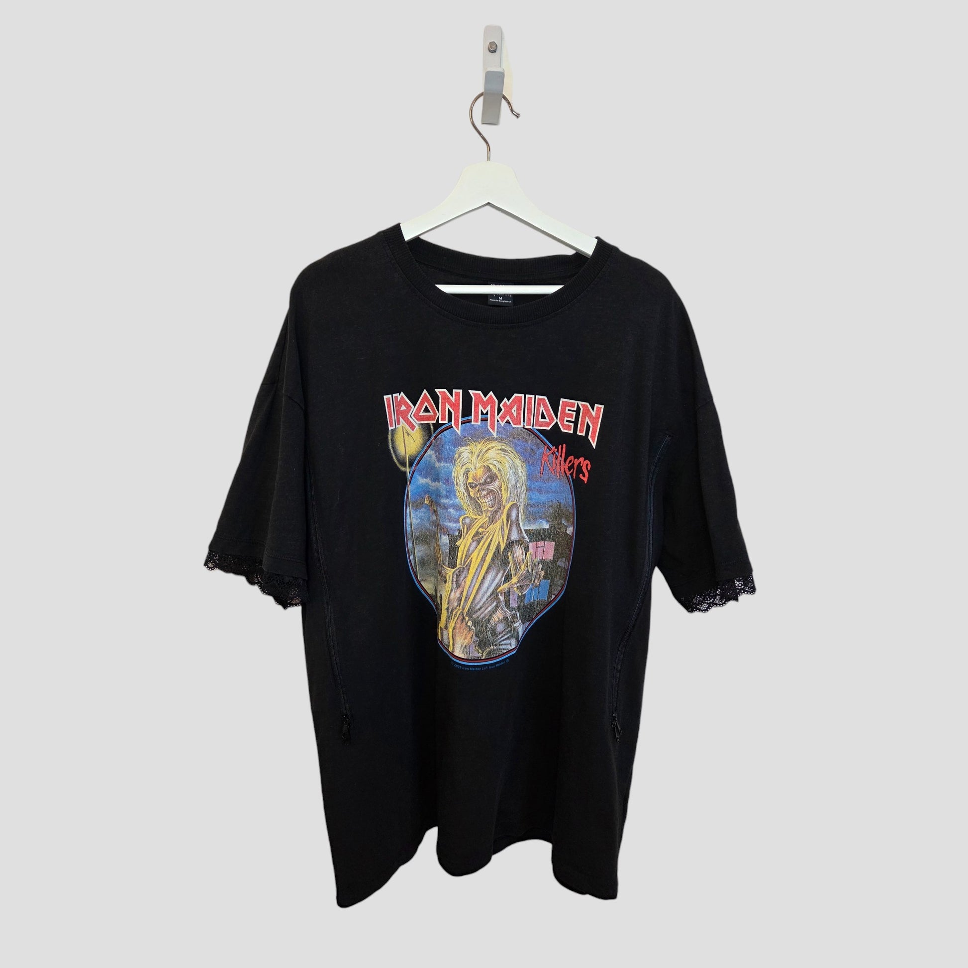 The Primark Upcycled Breastfeeding & Pumping Black Iron Maiden Oversized Band T-shirt (M, 100417) features the Killers album cover and offers a metal-inspired nursing option for moms. Shown on a white hanger against a light gray background.