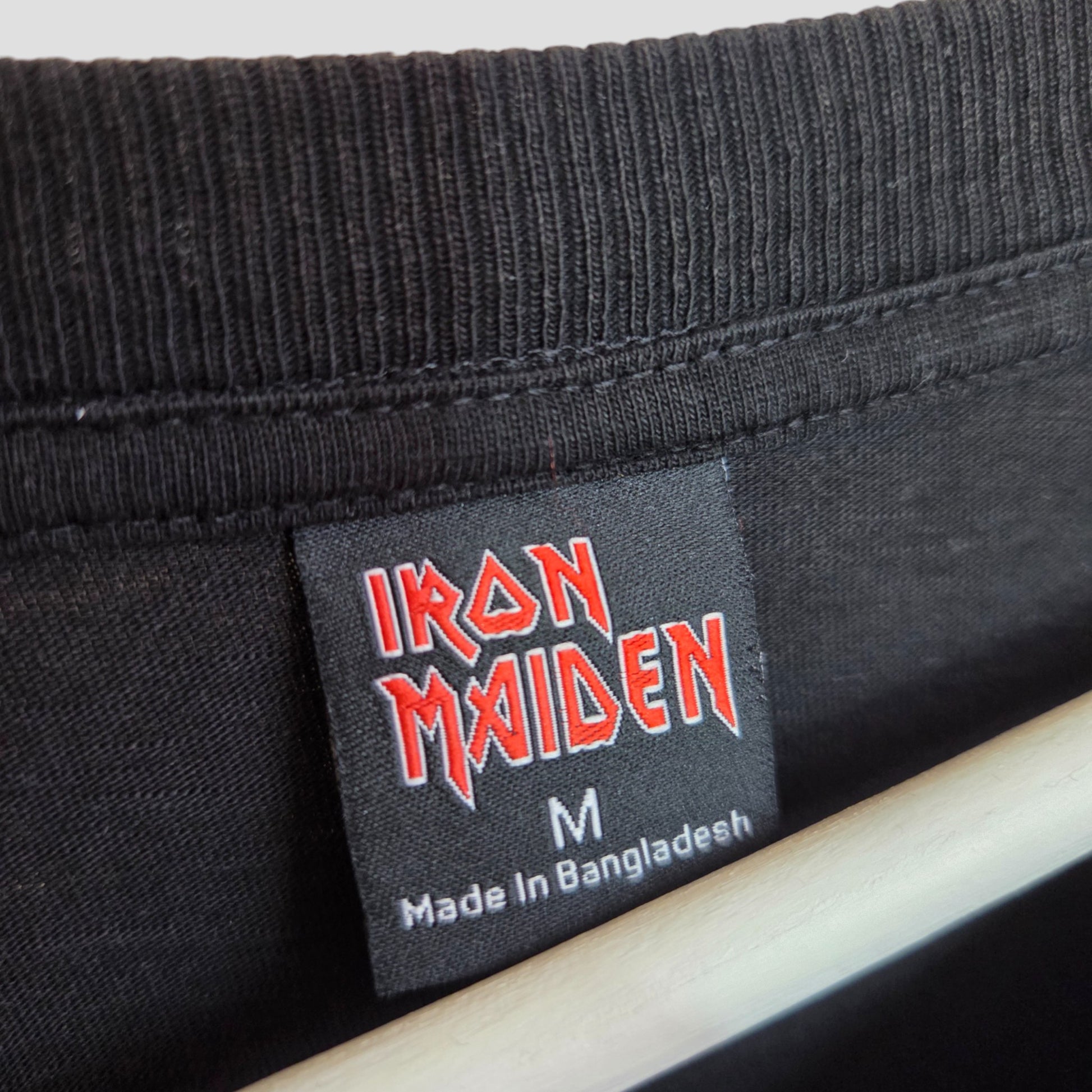 A close-up of a Primark label inside the collar of a black Iron Maiden oversized band T-shirt (size M, upcycled for breastfeeding and pumping), Made in Bangladesh—perfect for fans wanting unique nursing wear.