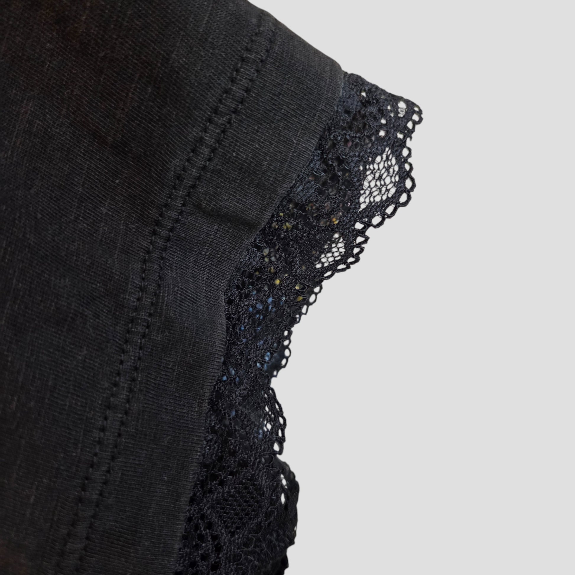 Close-up of an intricate lace-trimmed edge on the upcycled Primark Iron Maiden Oversized Band T-shirt (M, 100417), designed for breastfeeding and pumping, shown against a plain light gray background.