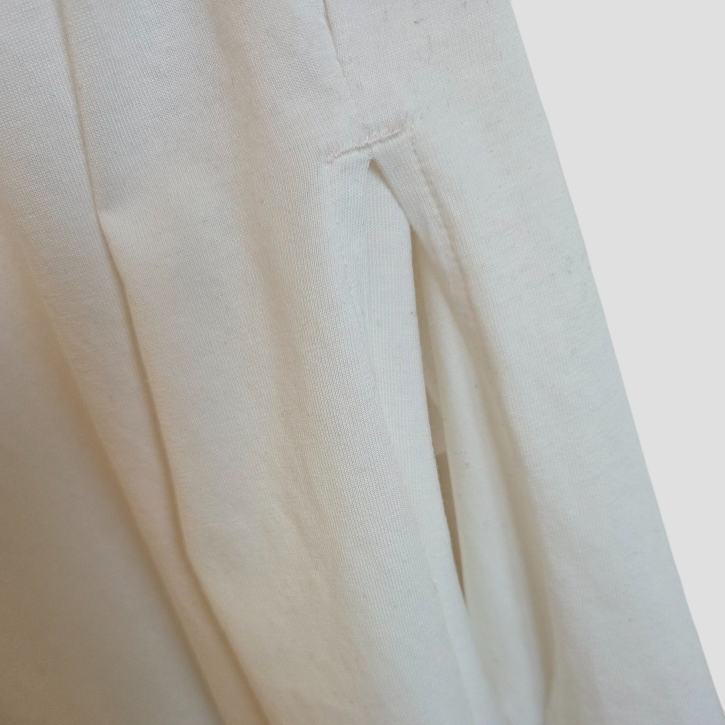 Close-up of Primark's Upcycled Breastfeeding & Pumping White/Black MAMA t-shirt (M, 100373), showcasing the texture, stitching, and a side seam pocket with a subtle pleat. Made from off-white eco cotton maternity fabric.