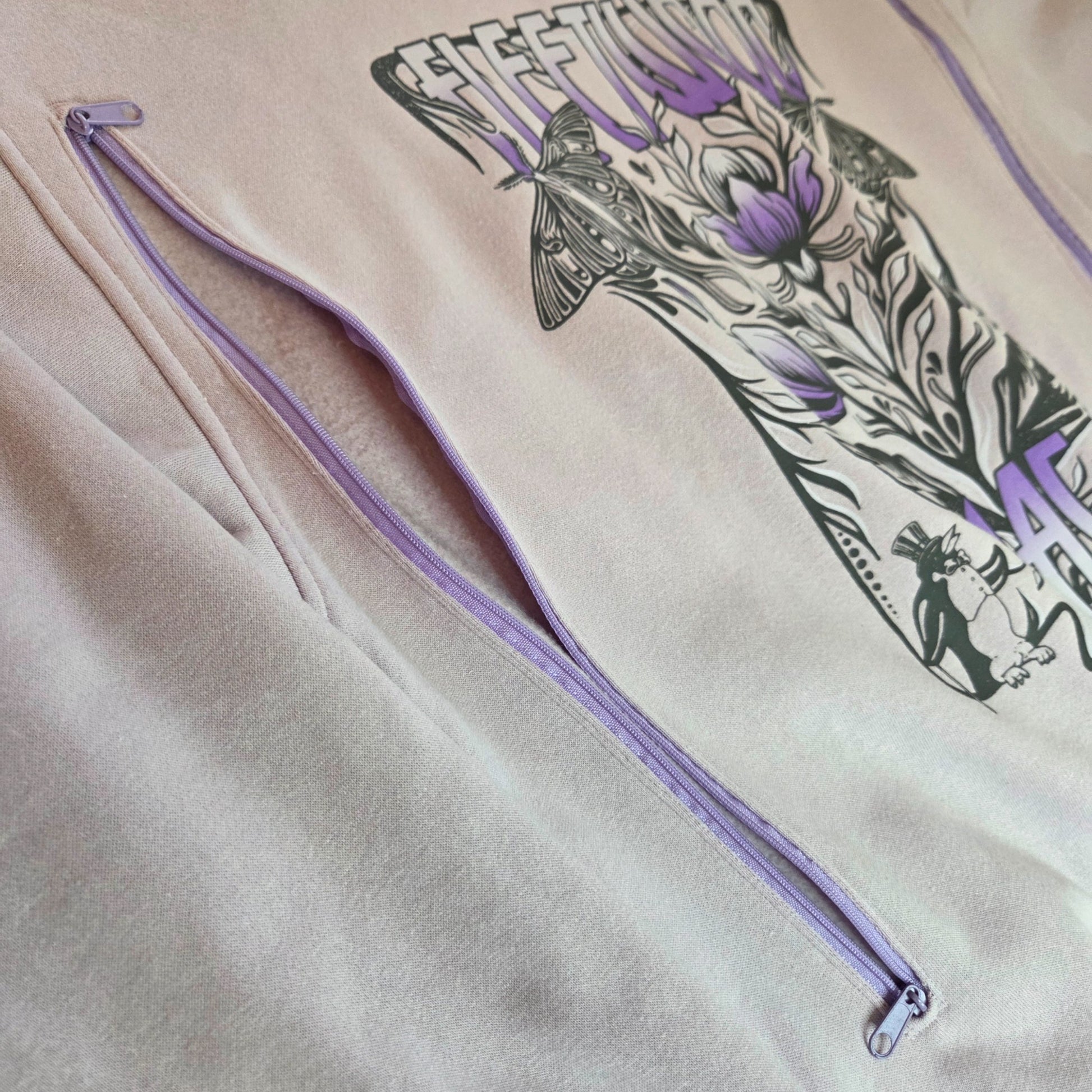 A close-up of an upcycled lilac H&M Fleetwood Mac band nursing sweatshirt in size M, featuring zip openings and decorative chest graphics—an eco-friendly and stylish choice for breastfeeding or pumping.
