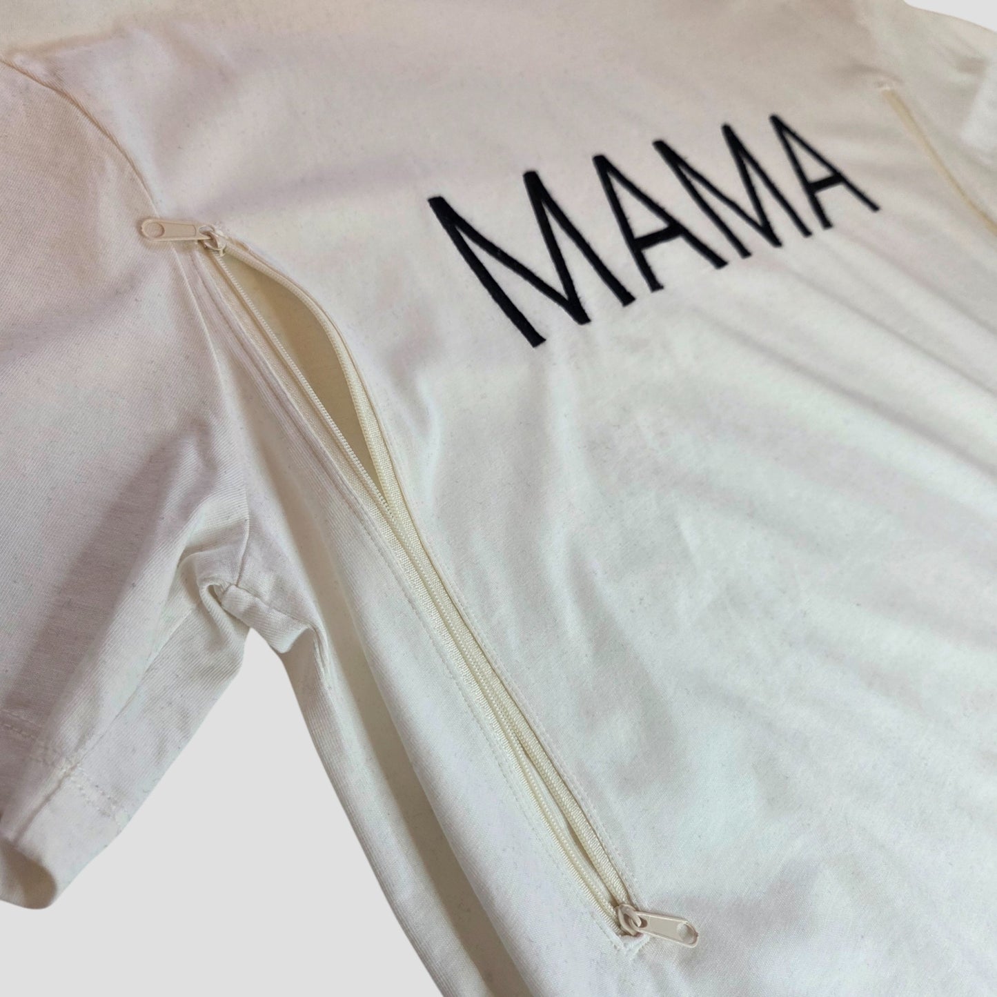 The Primark Upcycled Breastfeeding & Pumping White/Black MAMA t-shirt (M, 100373) is an eco cotton maternity shirt with "MAMA" in black on the chest and two vertical side zippers for convenient nursing.