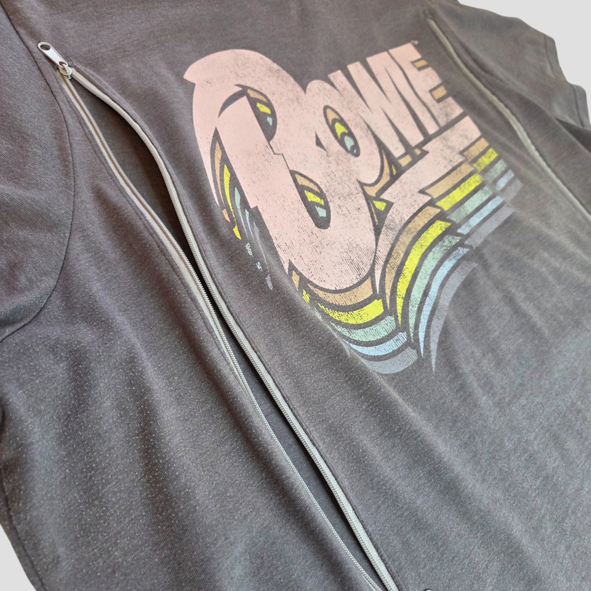 A close-up of Tu's Upcycled Nursing & Pumping Grey/Pastel Bowie Band t-shirt UK22 shows a retro faded logo and side zippers for added style, offering affordable fashion for plus sizes.
