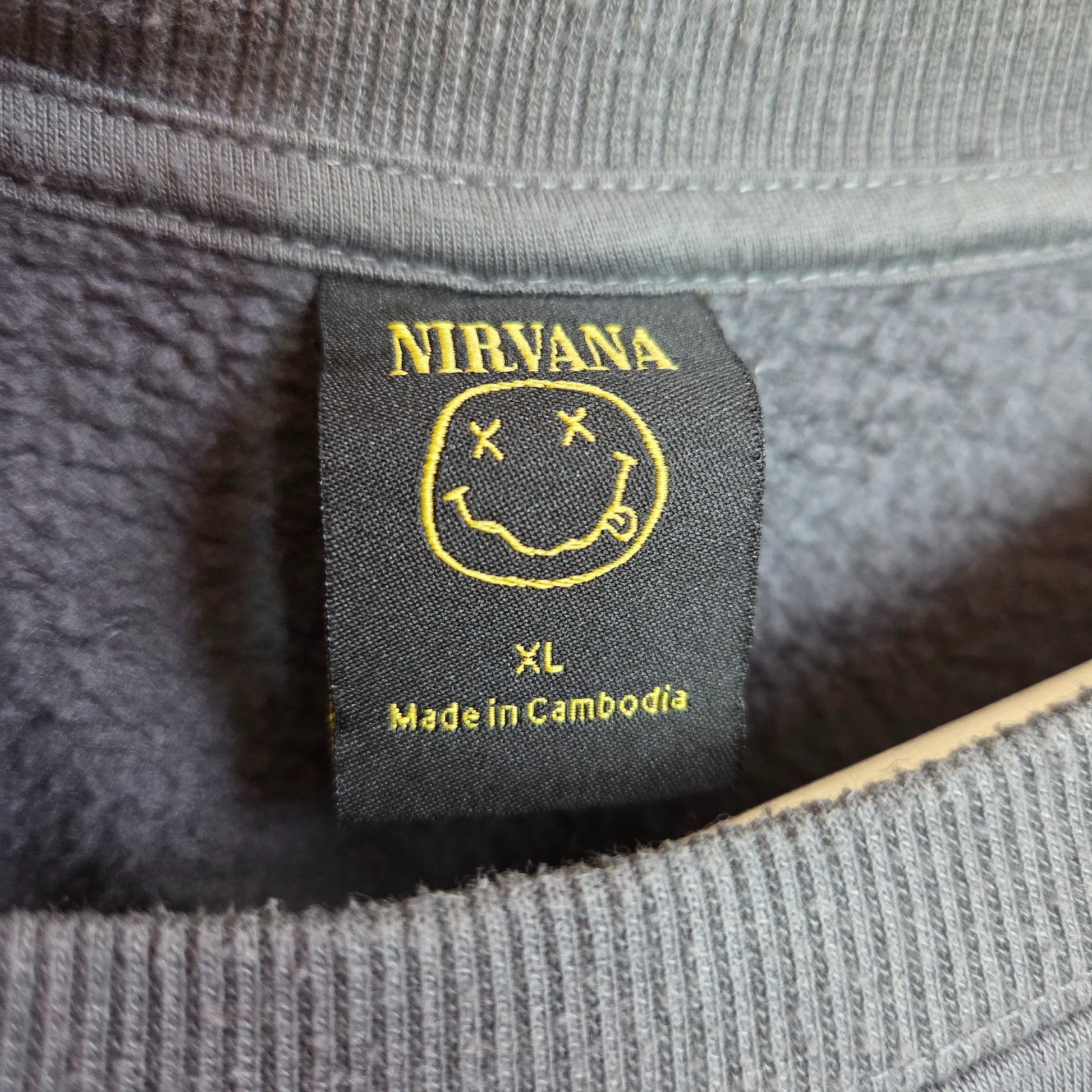 Close-up of a black Primark tag on an XL upcycled grey Nirvana Angel Band breastfeeding sweatshirt—perfect for fans seeking eco-friendly nursing or pumping wear. Made in Cambodia.