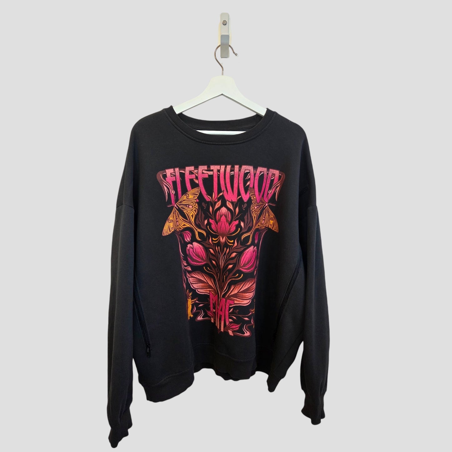 The Primark Upcycled Breastfeeding & Pumping Floral Fleetwood Mac Band Sweatshirt XL (UK18/20) features a colorful, psychedelic floral and moth graphic and hangs on a white hanger against a plain light gray background.