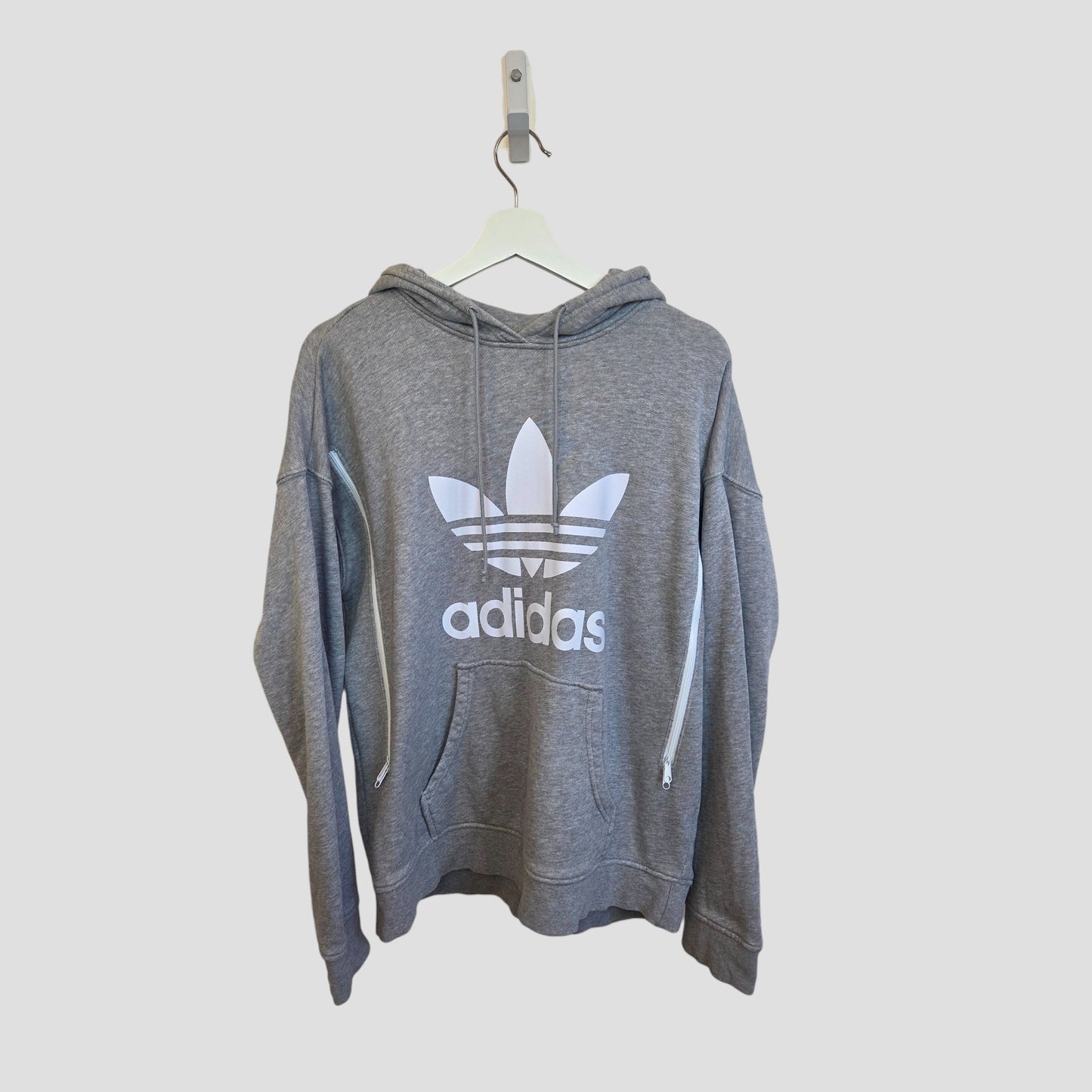 An upcycled grey/white Adidas Logo Breastfeeding & Pumping Hoodie (UK12, 100408) by Adidas hangs on a white hanger against a plain light background.