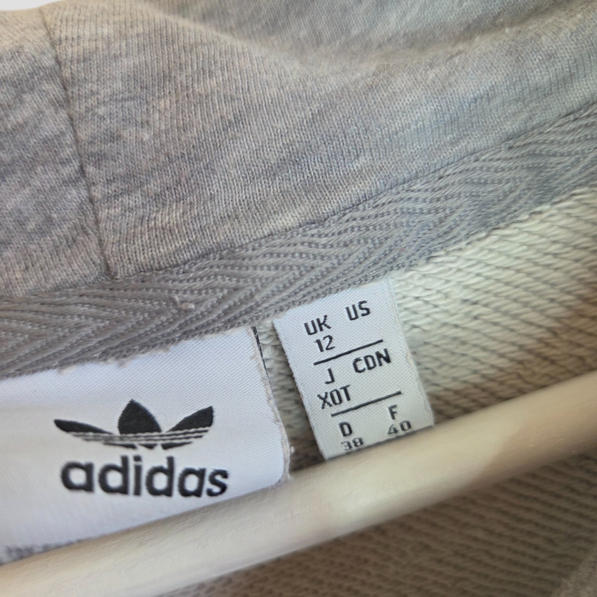 Close-up of an upcycled Adidas Breastfeeding & Pumping Grey/White Logo Hoodie (UK12), showcasing its collar, white size tag, and visible logo—ideal for eco-conscious nursing or pumping moms.