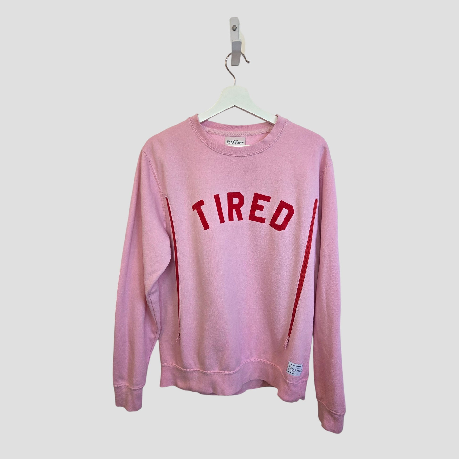 The Tired Mama Collection Upcycled Breastfeeding & Pumping Pink Tired Mama Sweatshirt UK14 (100429)—a stylish, eco-friendly choice for maternity wear with bold “TIRED” lettering across the chest.