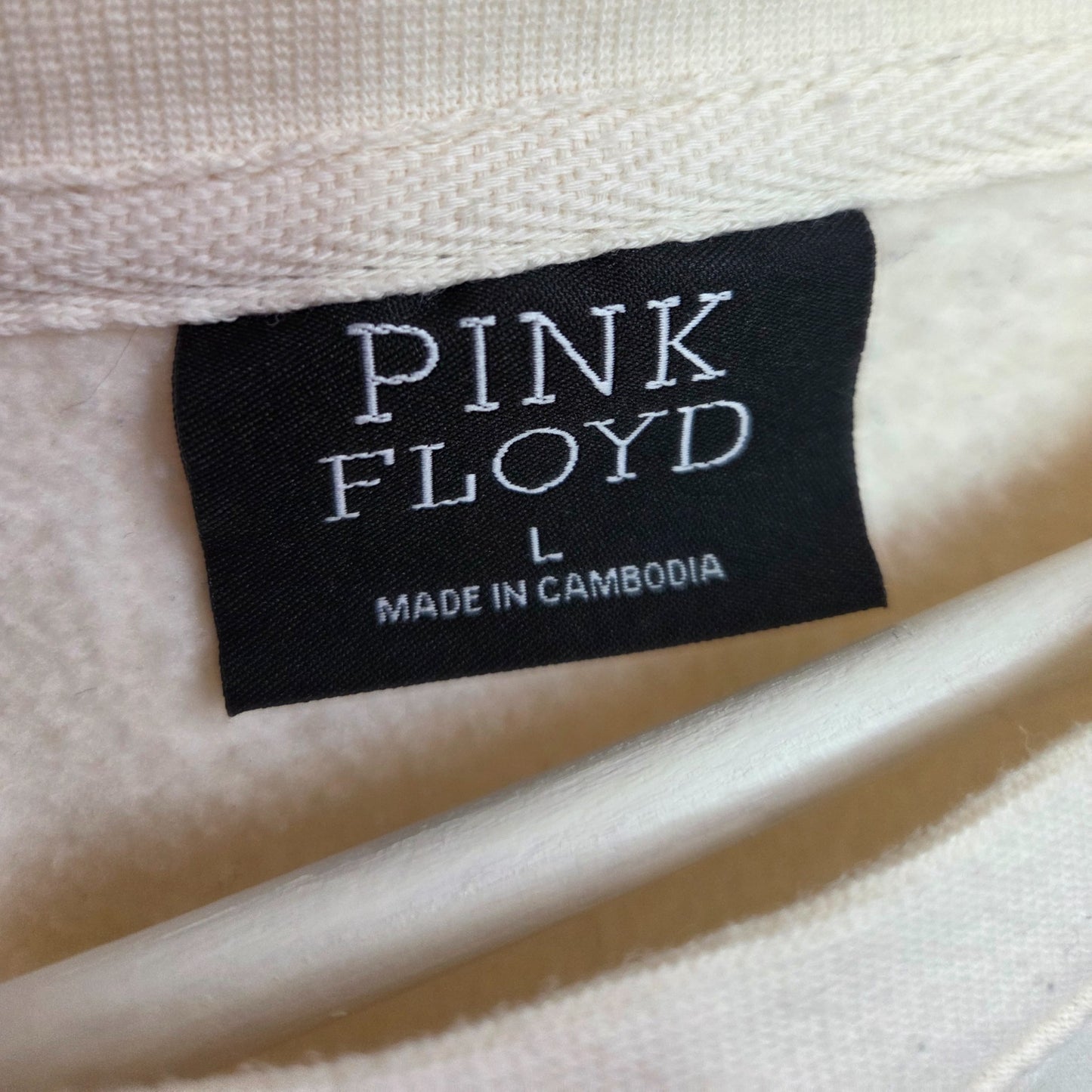 A black Primark tag on a cream Pink Floyd Band Nursing & Pumping Sweatshirt (size L) reads “PINK FLOYD” and “MADE IN CAMBODIA”—a great preloved find for breastfeeding fans seeking unique style.