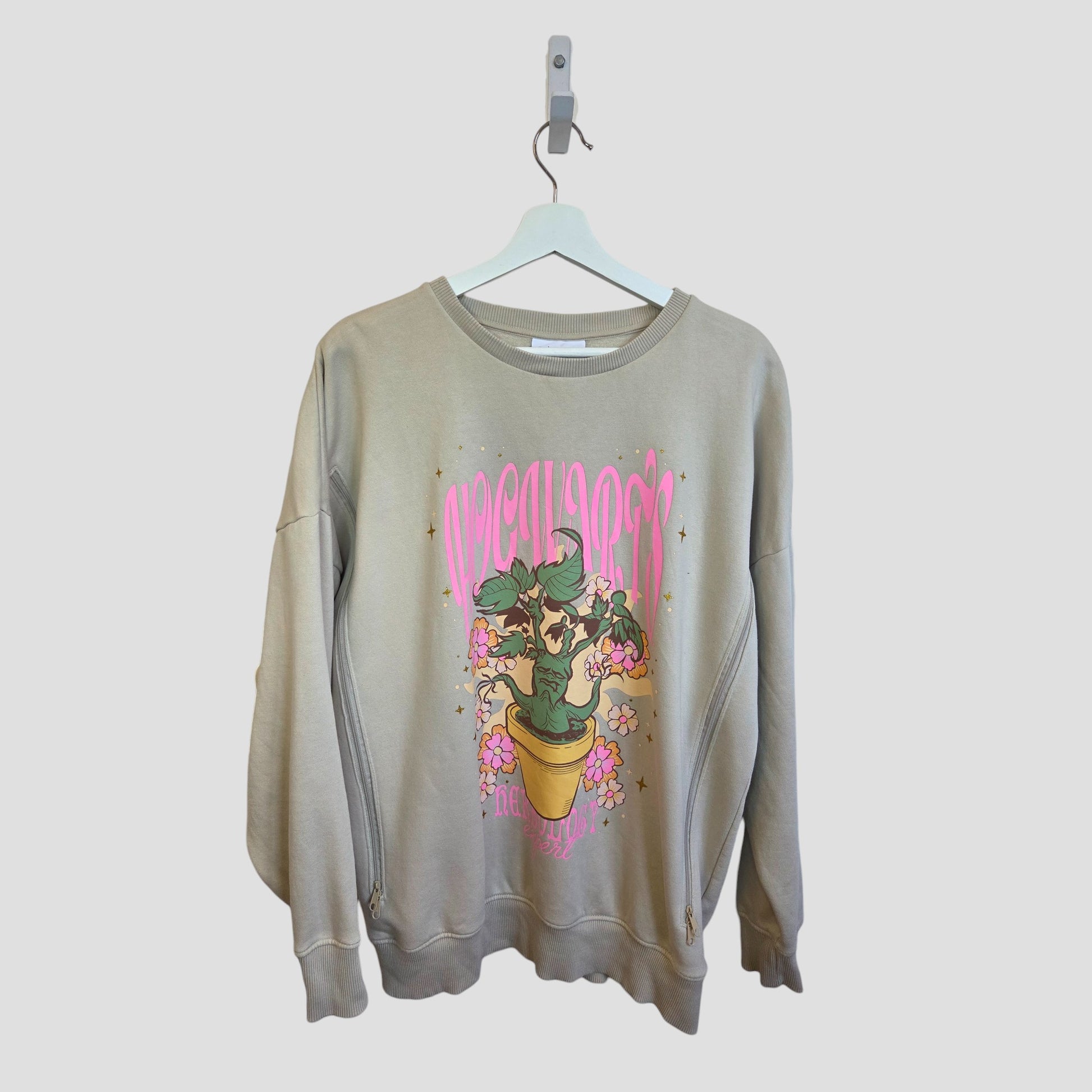 A beige Harry Potter sweatshirt by George, size M (UK12/14), upcycled for breastfeeding and pumping, features colorful plant graphics with flowers, sparkles, and bold pink text—eco-friendly maternity fashion on a white hanger.