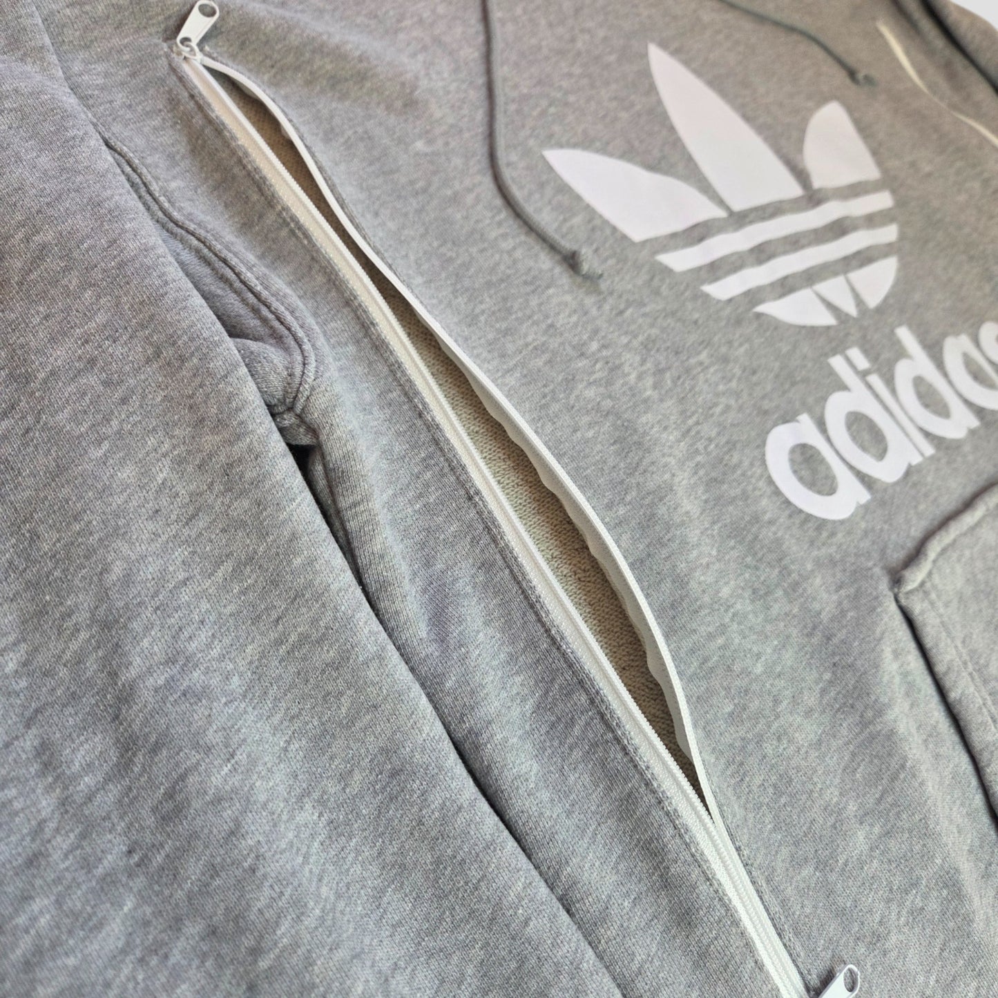 Close-up of an upcycled Adidas Grey/White Logo Hoodie UK12 (100408) featuring a side zipper for breastfeeding or pumping—perfect preloved choice for nursing comfort and style.