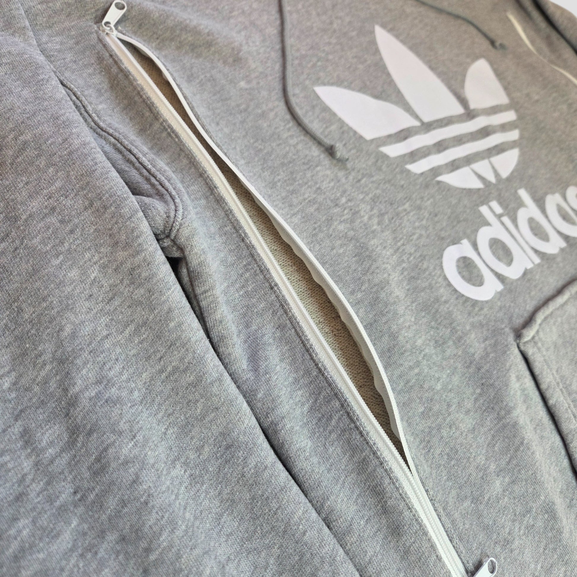 Close-up of an upcycled Adidas Grey/White Logo Hoodie UK12 (100408) featuring a side zipper for breastfeeding or pumping—perfect preloved choice for nursing comfort and style.