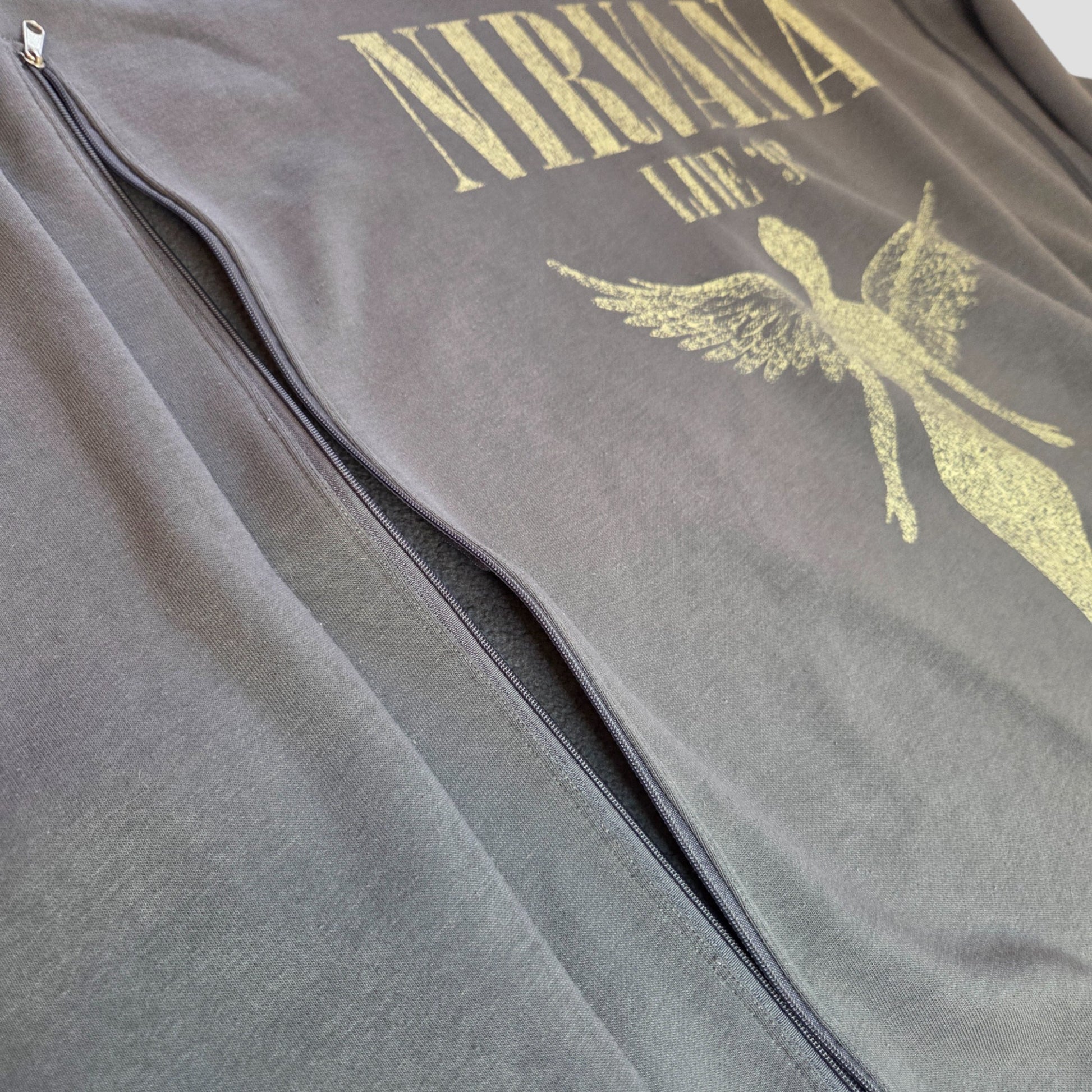 A close-up of an upcycled grey Nirvana Angel Band sweatshirt by Primark, size XL, designed for breastfeeding and pumping, with a front angel graphic and discreet zipper details.
